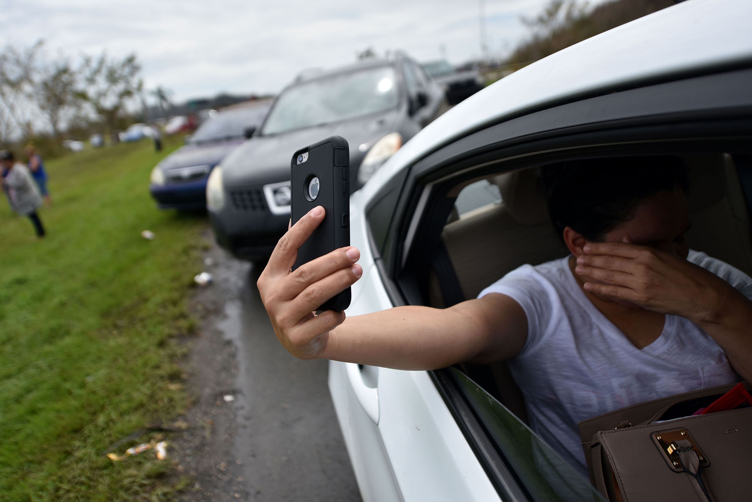 A woman tries to make a call from her car, pulled over on a highway north of San Juan, Puerto Rico after Hurricane Maria devastated the island’s communications infrastructure.