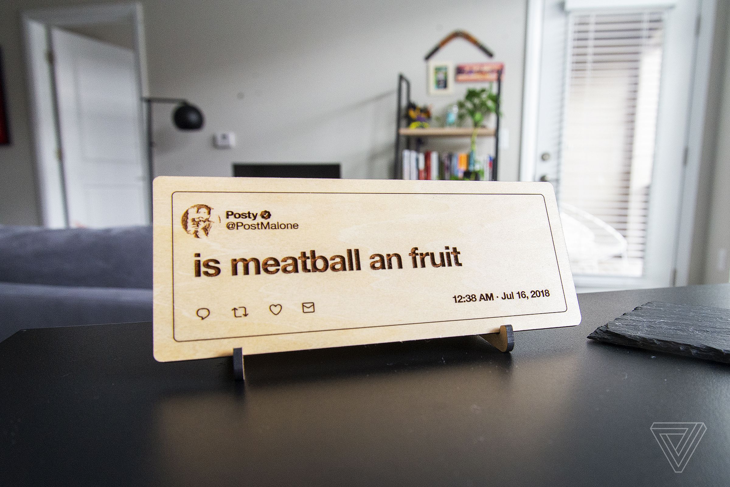 A wooden plaque sitting on a desk that reads “is meatball an fruit”