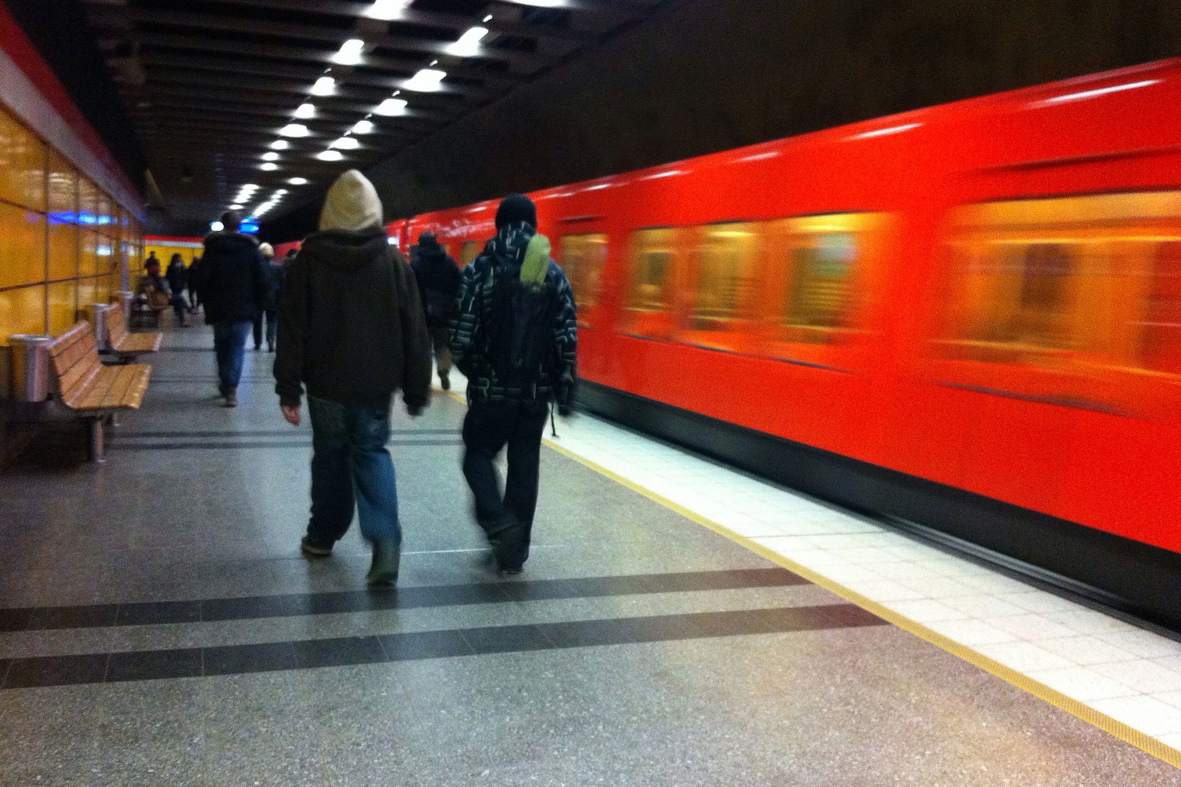 Commuters walk through a Helsinki Metro station as a train passes