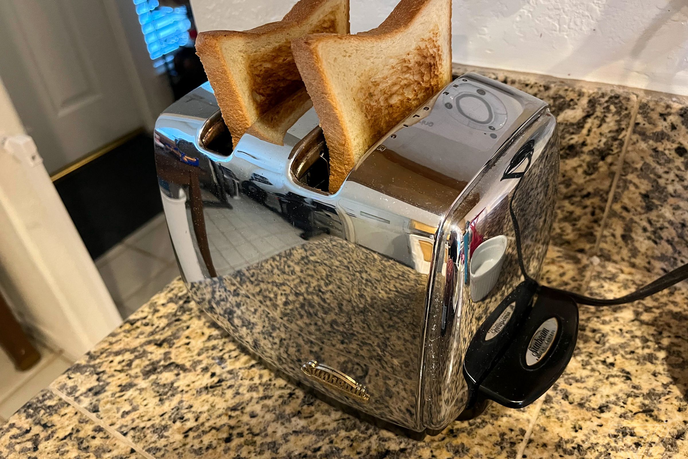 Shiny metal toaster with two pieces of toast popped out.