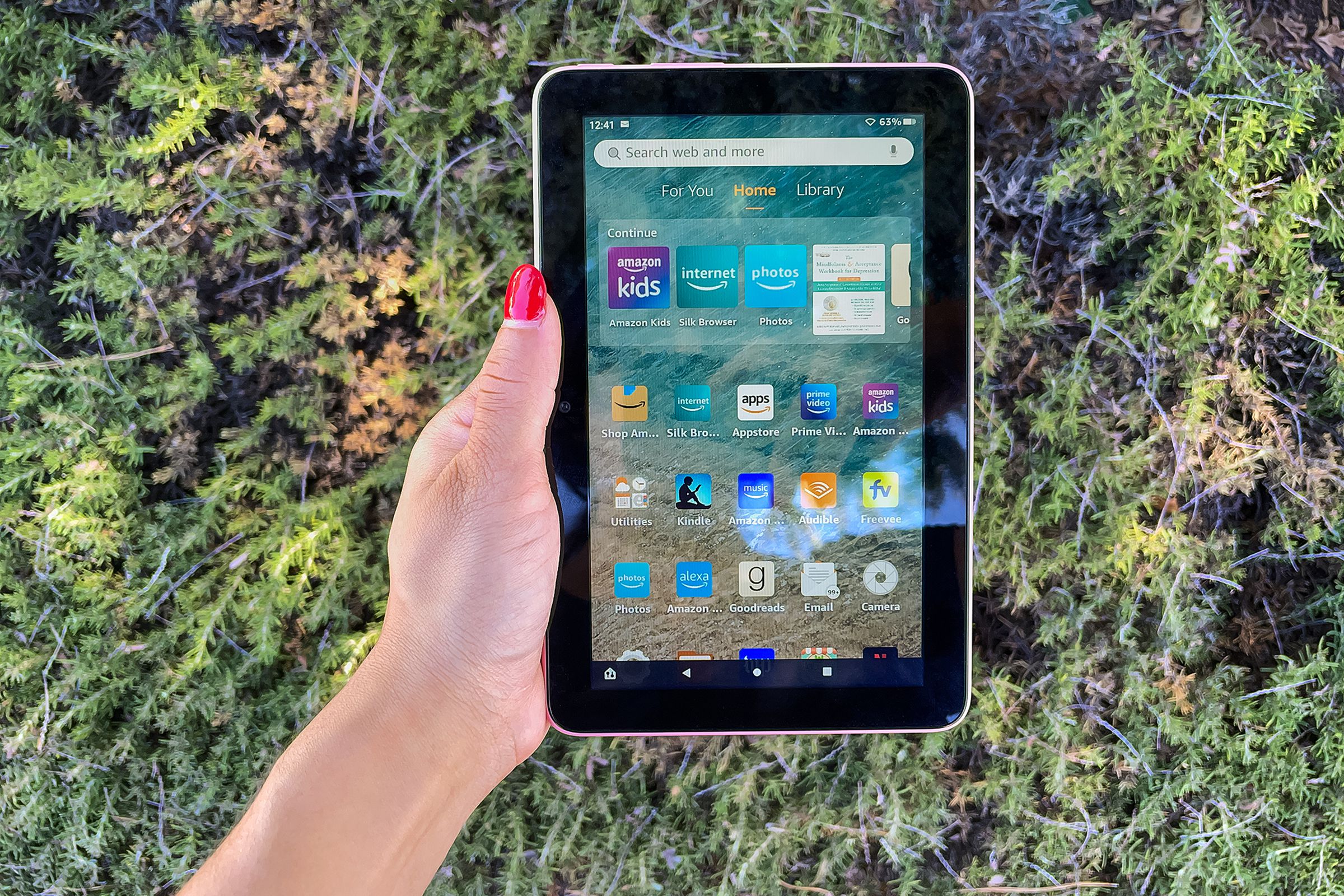 A hand holding Amazon’s Fire 7 tablet while its screen is turned on.