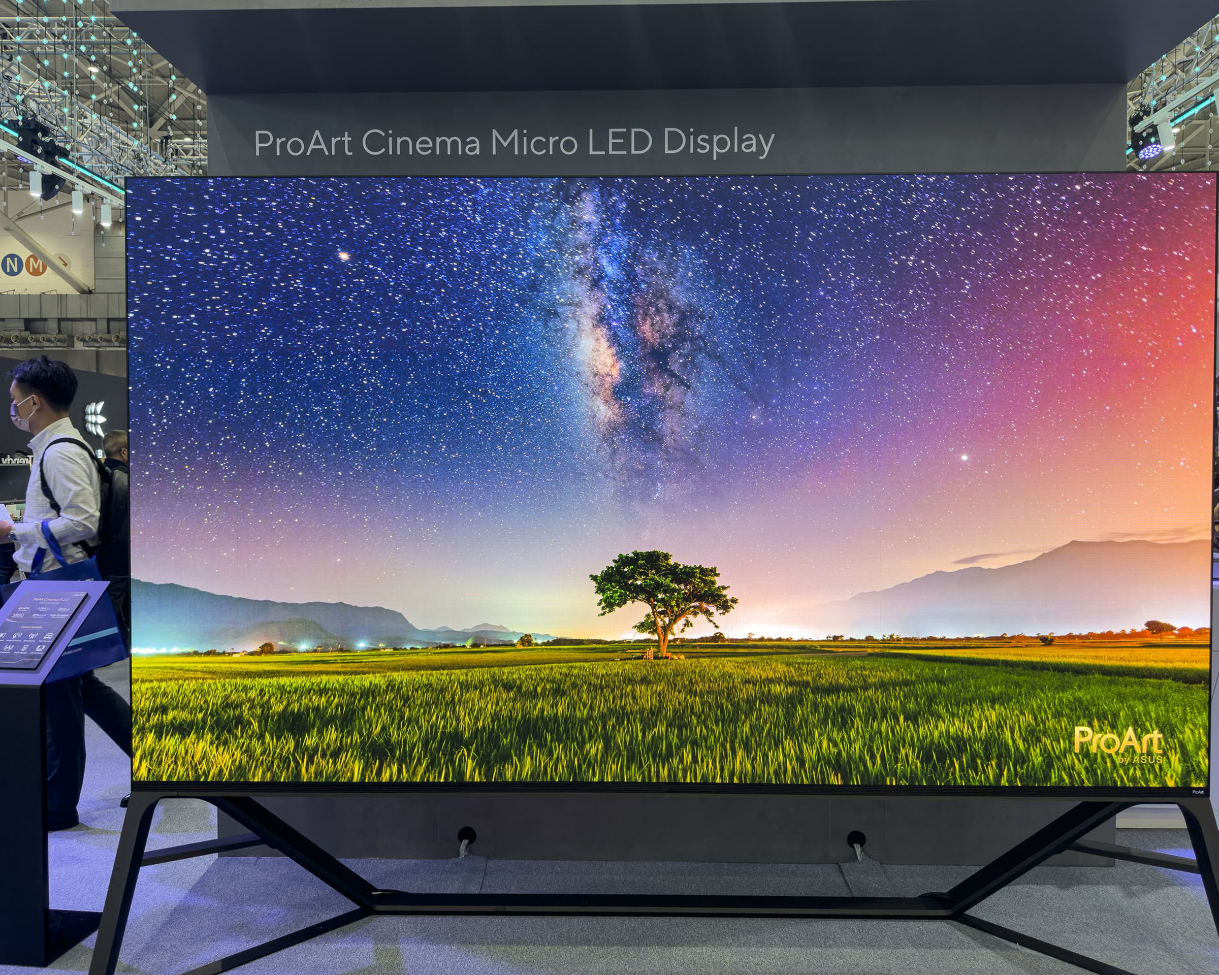 The Asus ProArt Cinema PQ07 displaying an outdoor scene with a tree and a colorful sky on the Computex 2023 show floor.