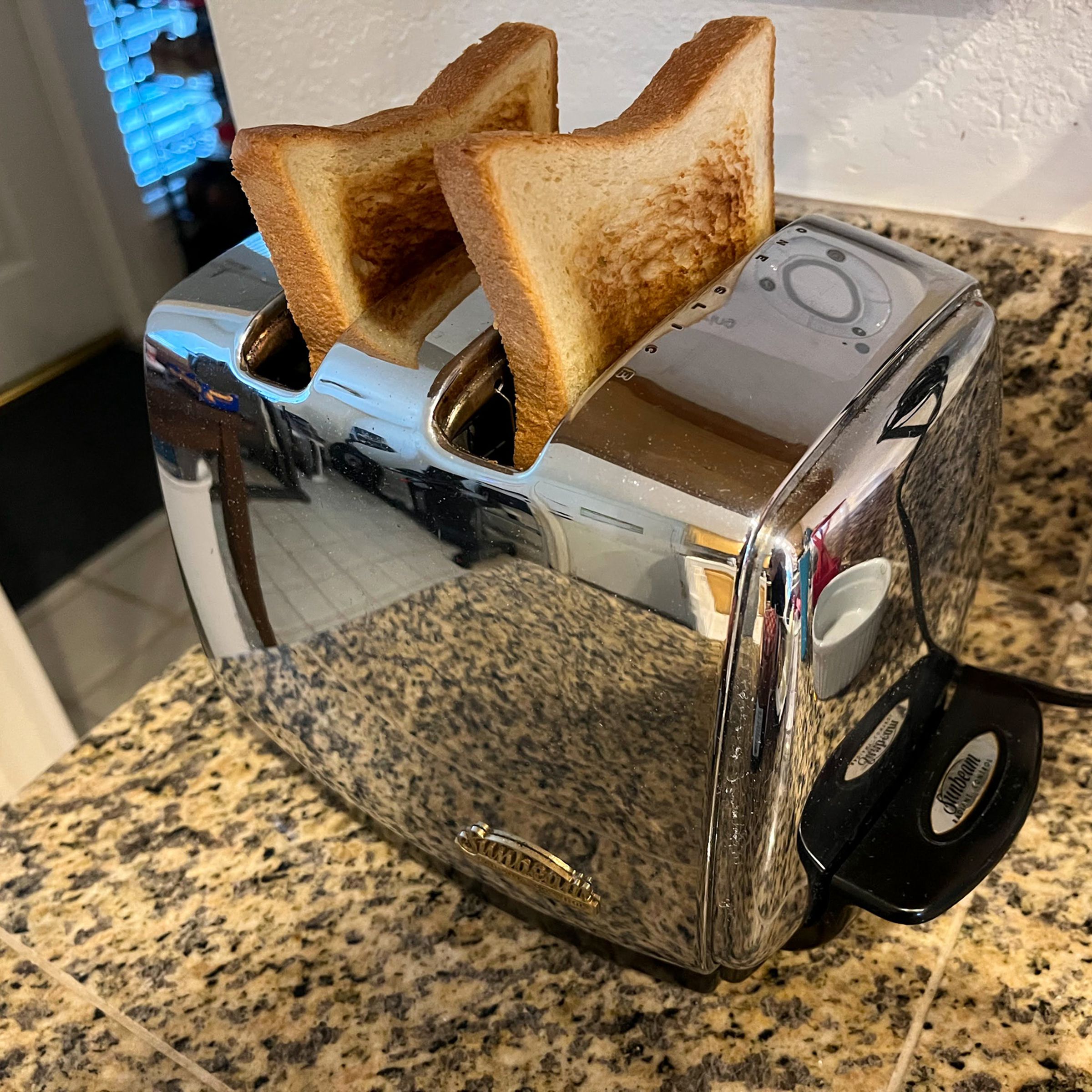 Shiny metal toaster with two pieces of toast popped out.