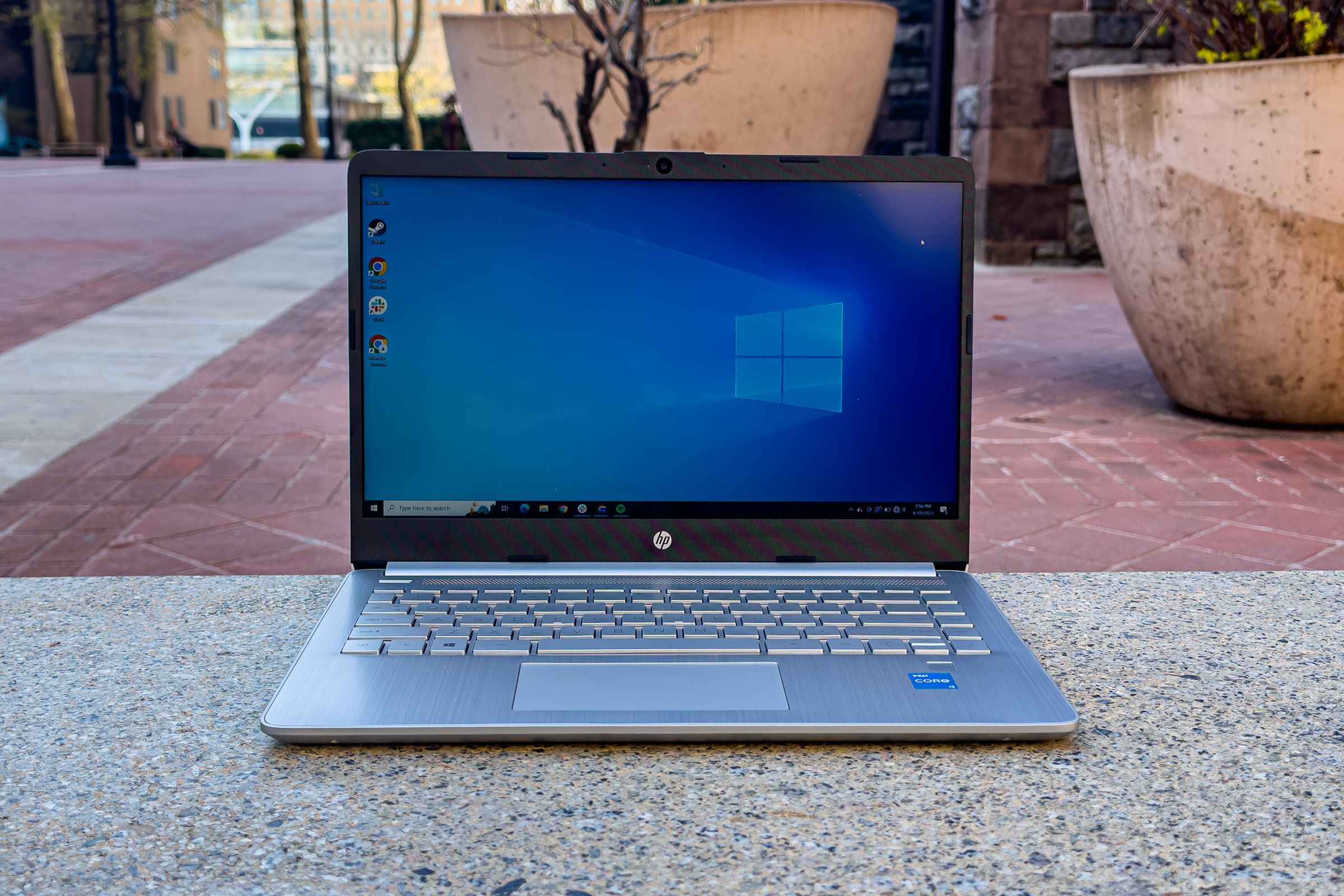 The HP 14 open in an outdoor setting displaying the Windows default desktop background.