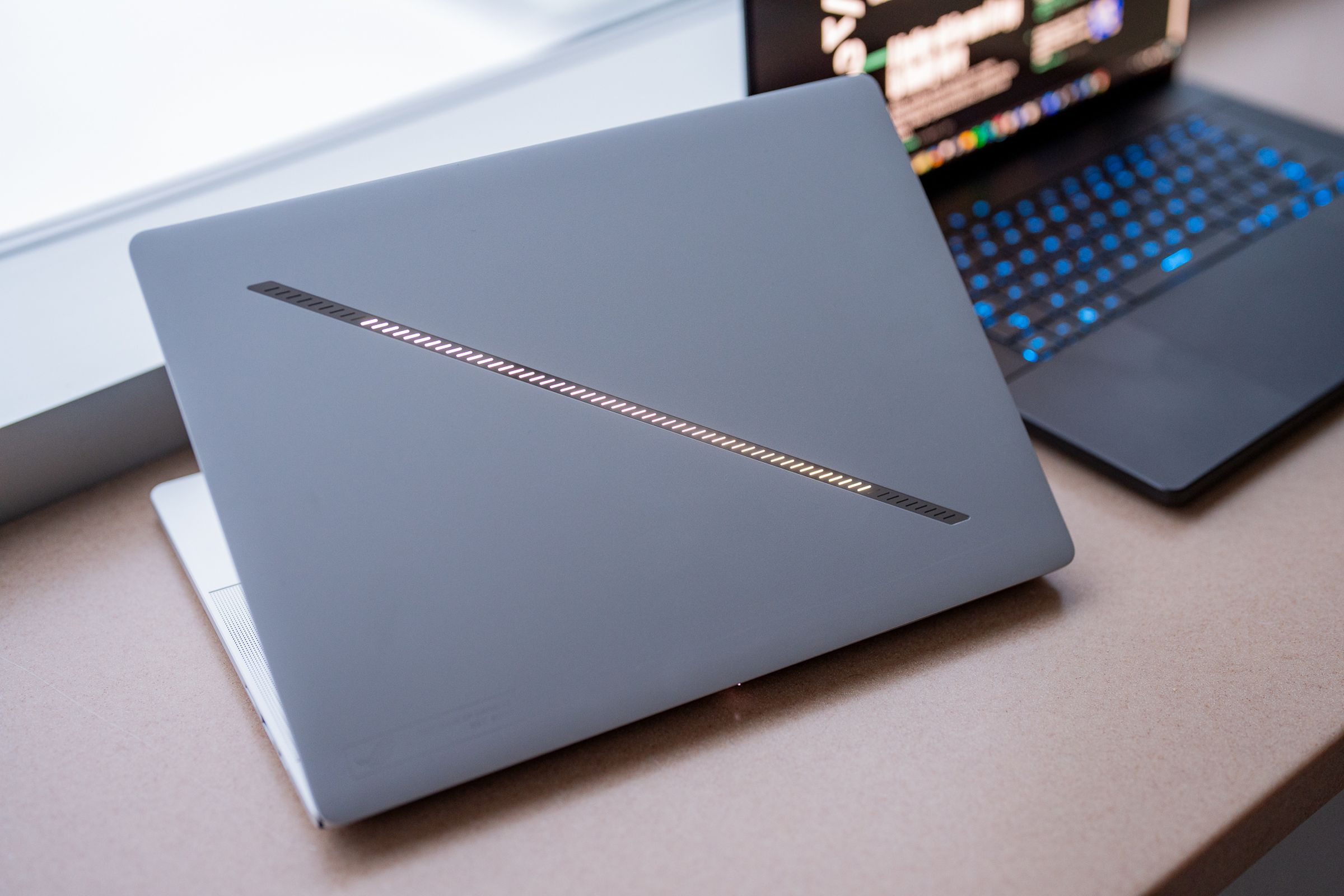 A silver laptop with a bright slash down the front. The slash has a series of RGB LEDs down the middle, but looks a little more restrained than previous ROG Zephyrus models.
