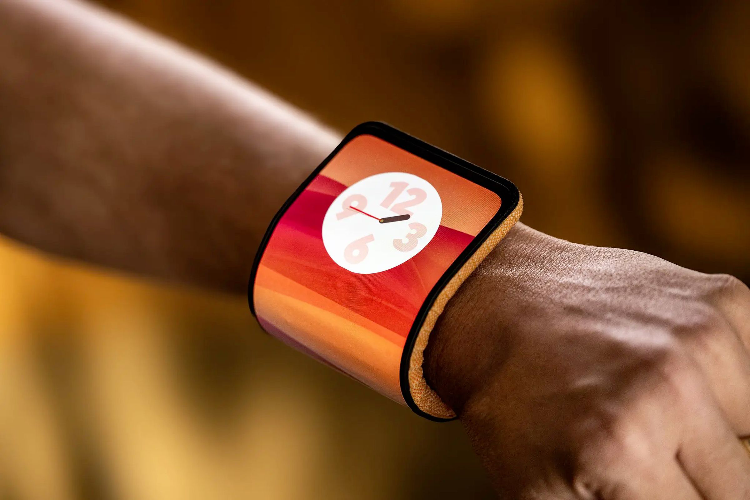 Close-up of a Lenovo bendable phone concept on a person’s wrist. The phone has an orange fabric on the back.