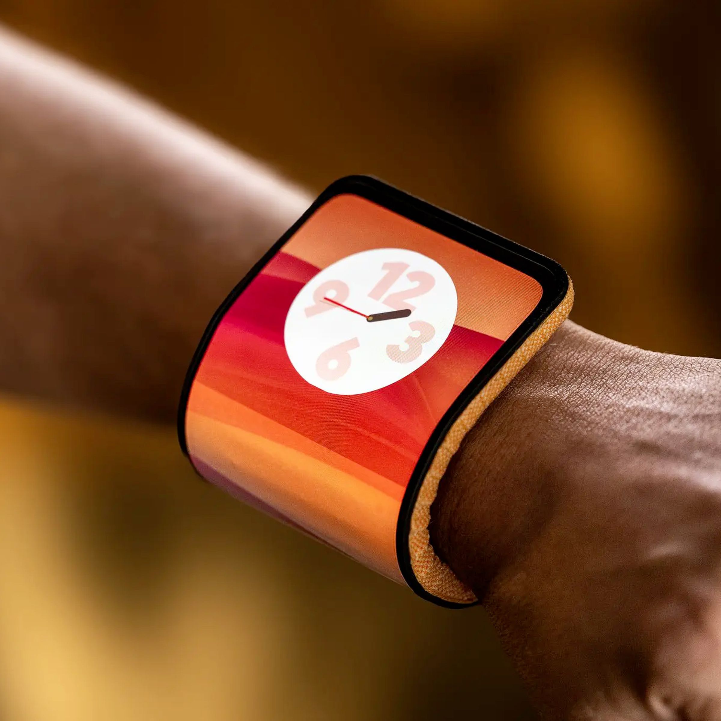 Close-up of a Lenovo bendable phone concept on a person’s wrist. The phone has an orange fabric on the back.
