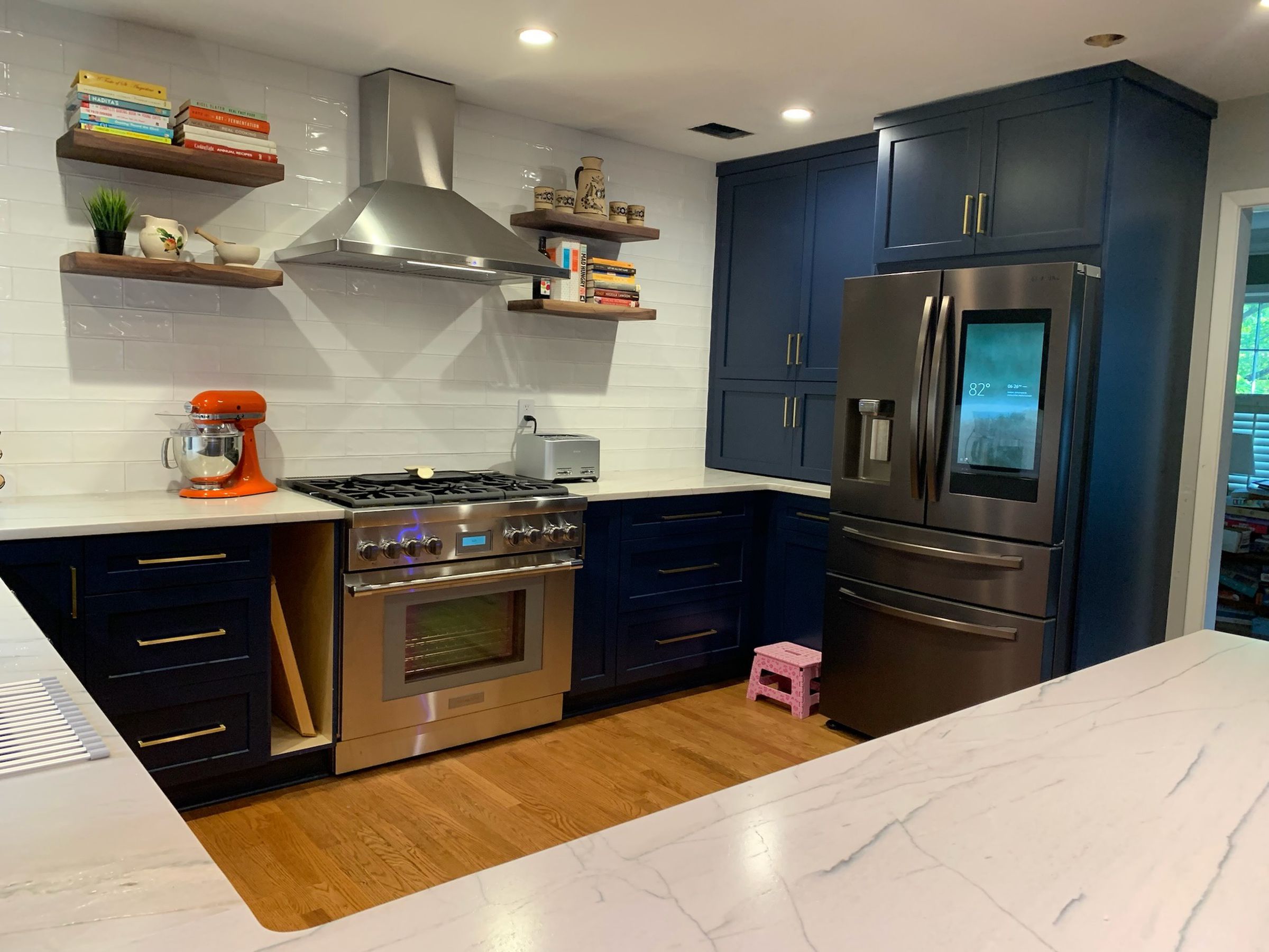 A kitchen scene featuring a silver metal oven and a fridge with a screen.