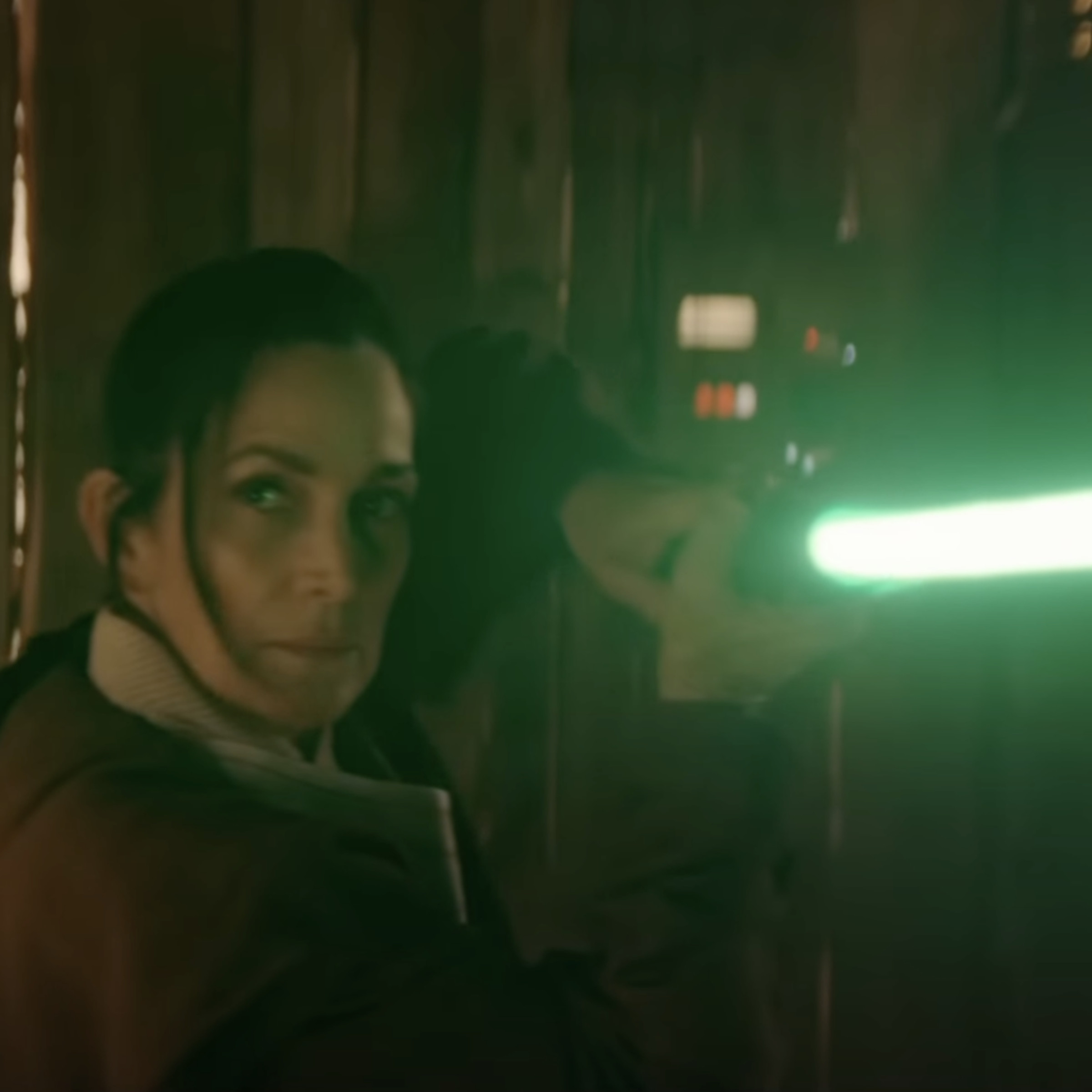 A screenshot showing Carrie-Anne Moss’s character wielding a green lightsaber.