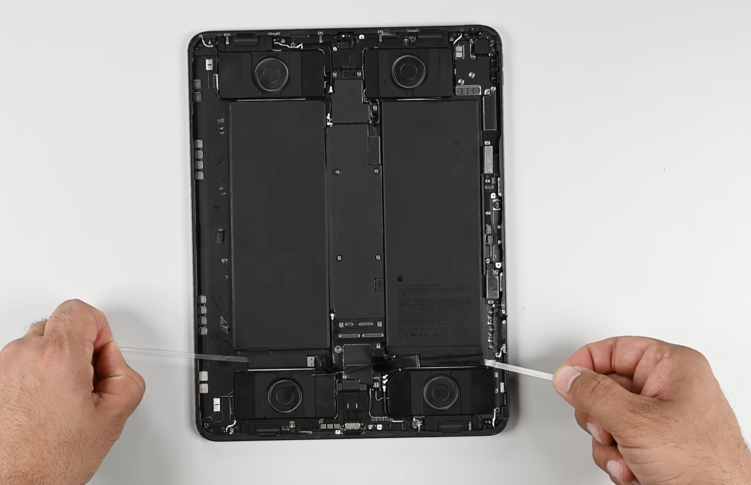 Screenshot of the iPad Pro with screen off and two hands pulling at pull-tabs on either side near the bottom.