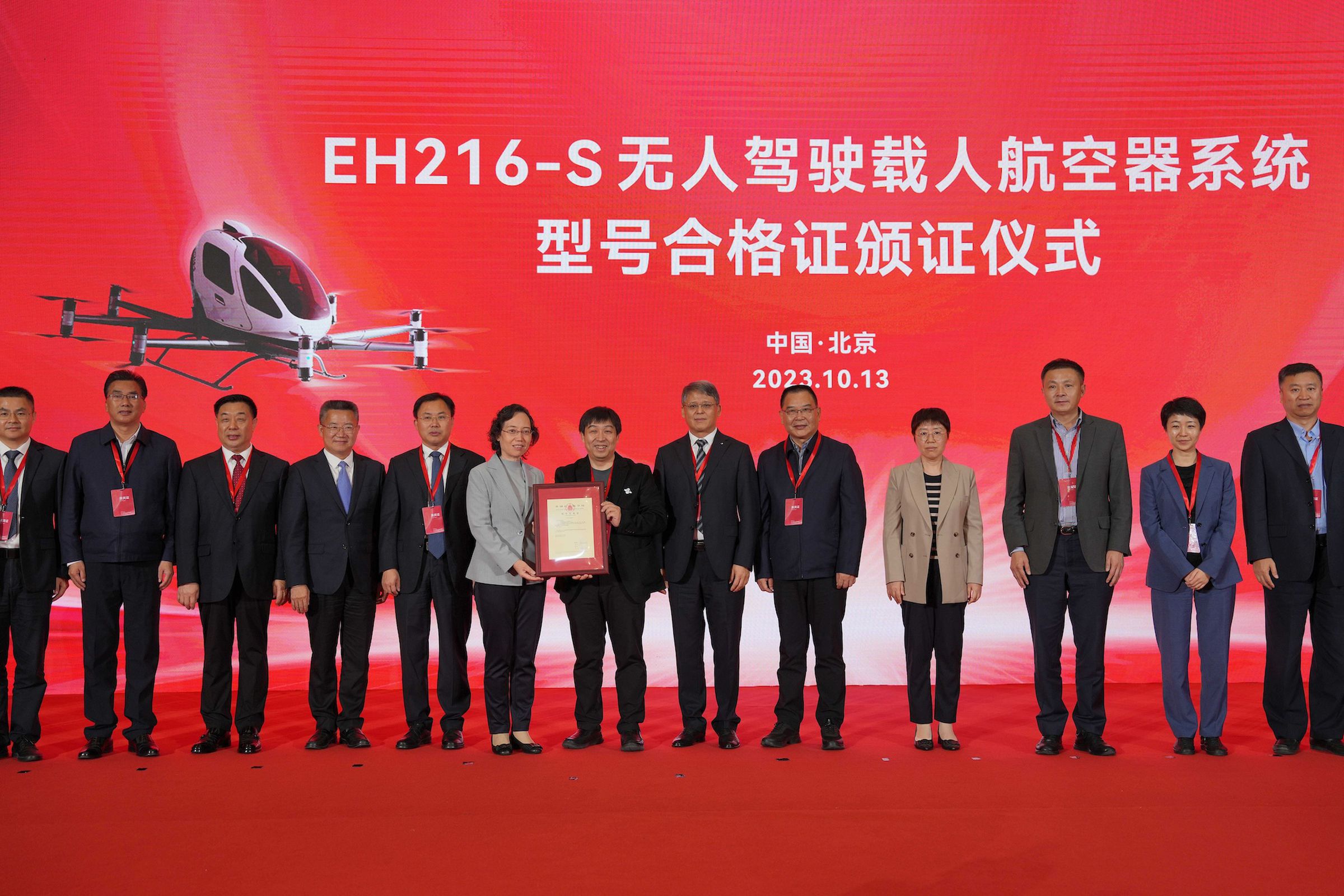 A picture of EHang Holdings executives lined up in a row in front of a red backdrop holding the new certification.