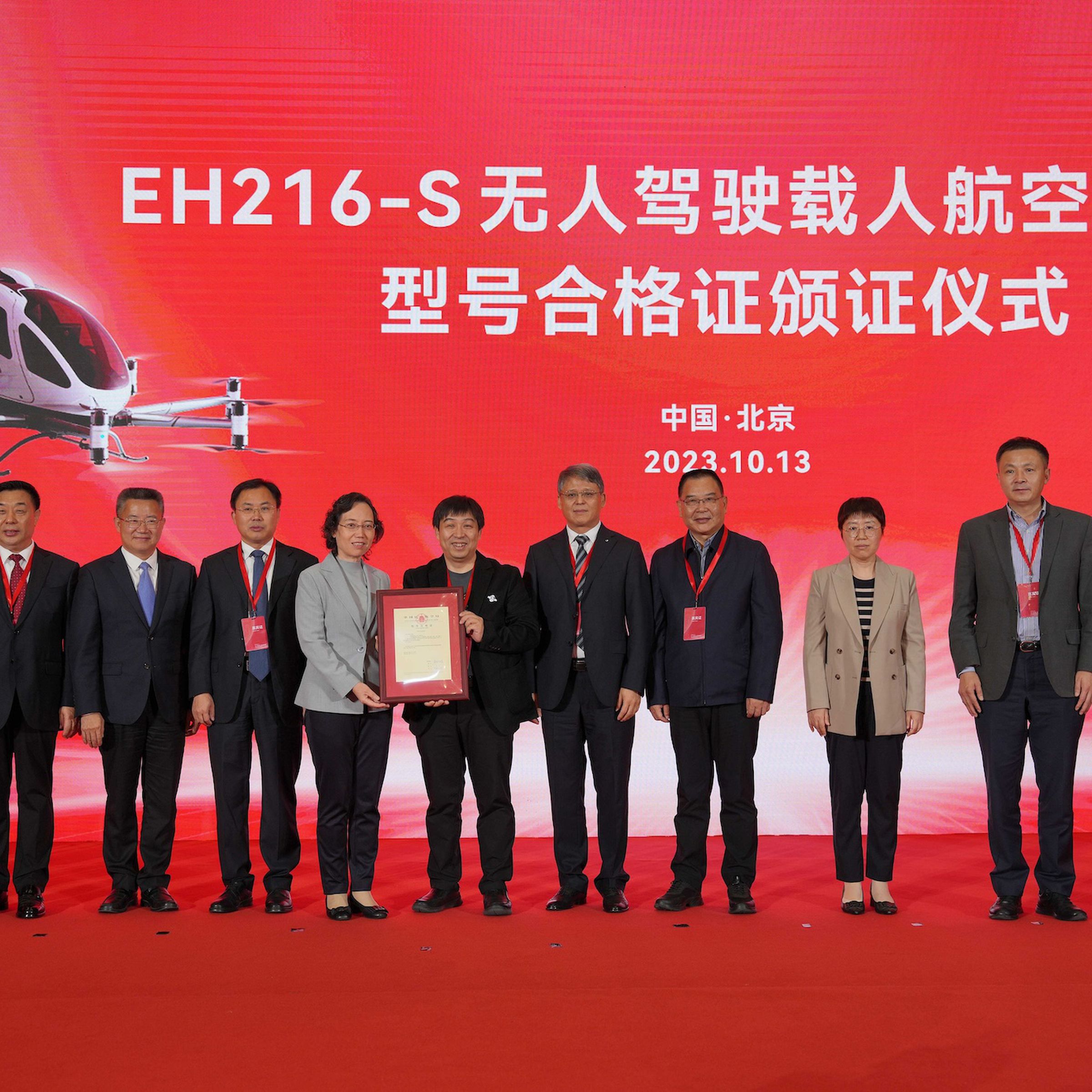 A picture of EHang Holdings executives lined up in a row in front of a red backdrop holding the new certification.