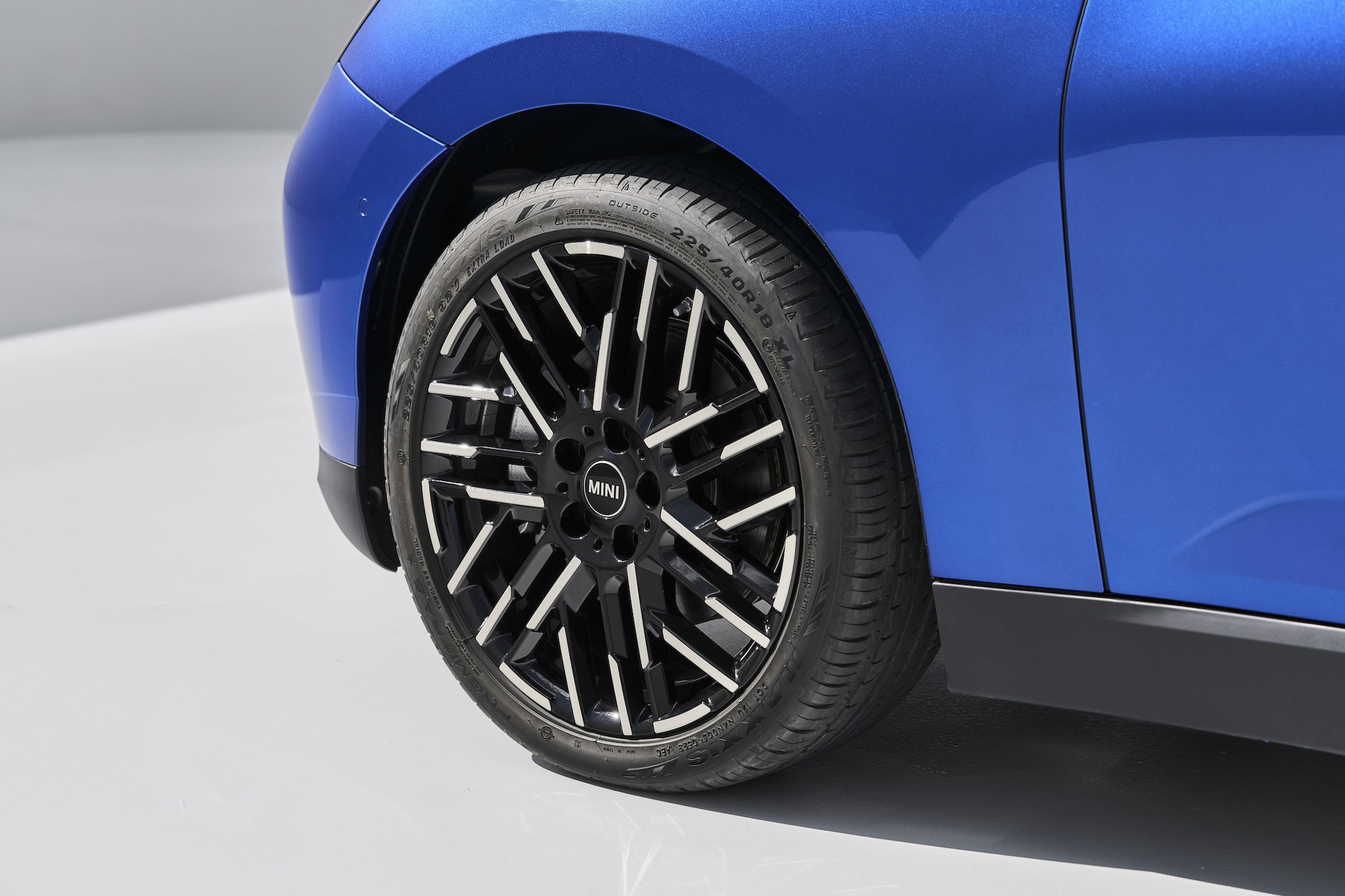 Close-up of the Mini Cooper’s front left wheel, which is black with several short, silver lines.