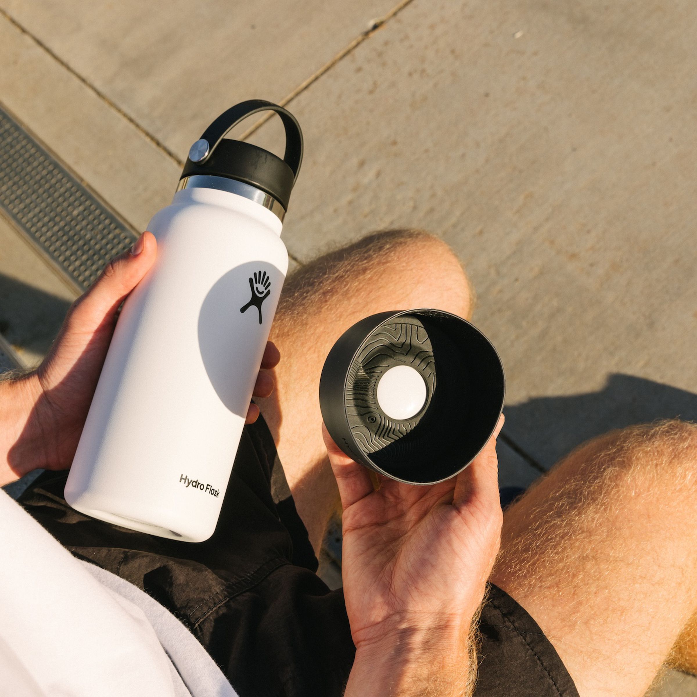 A picture of a person holding the Hydro Flask with a Flex Bot and the tracker inside of it, with an AirTag inside of that.