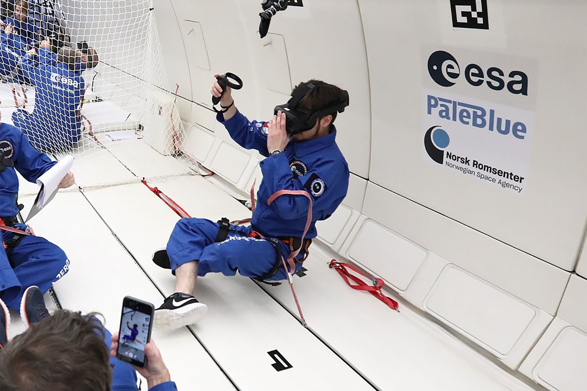 A person “sits” cross-legged while floating above the floor of a plane during a parabolic flight.