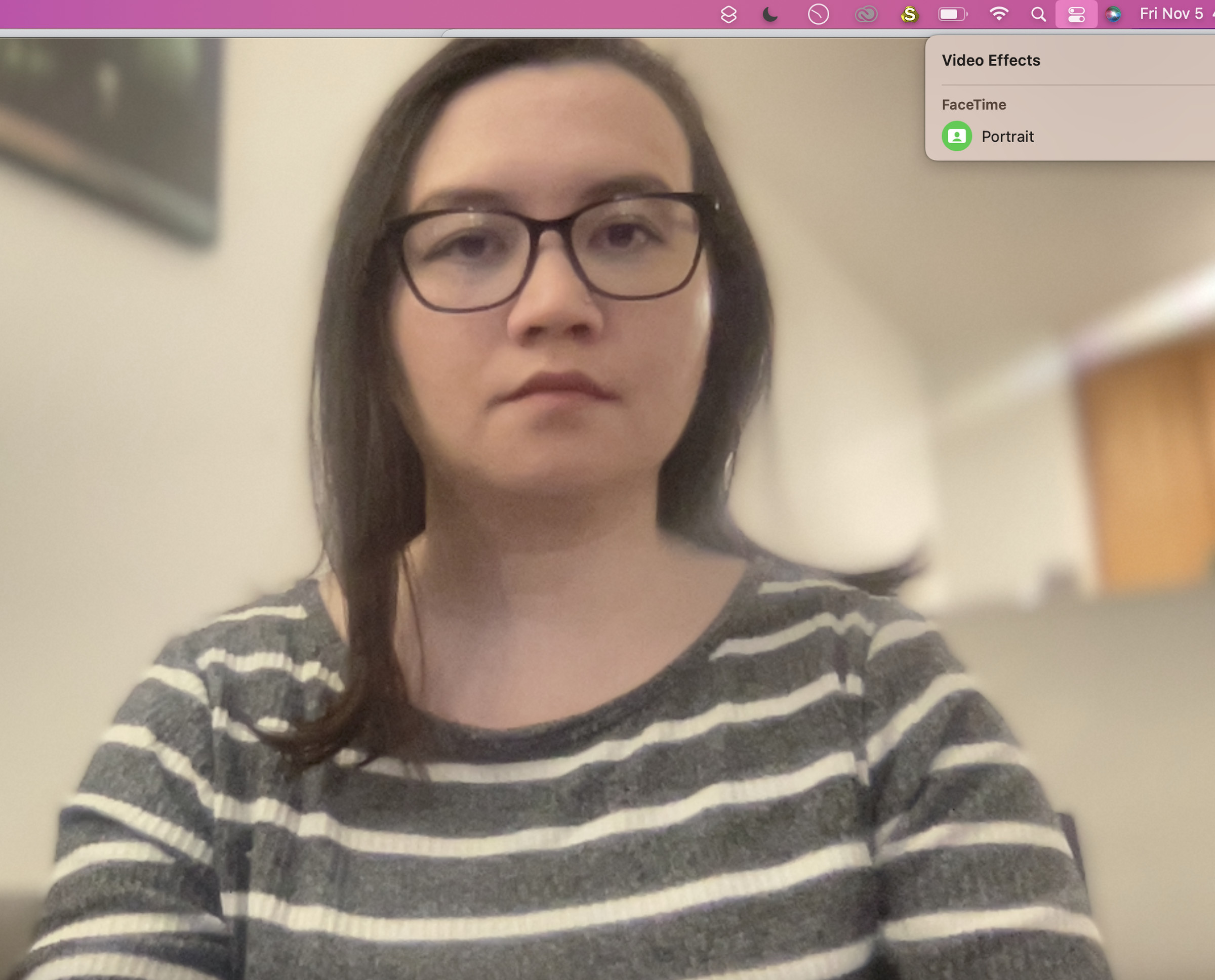A user faces the camera on a FaceTime call with their background blurred out. A drop-down menu from the Control Center indicates that Portrait Mode is active.
