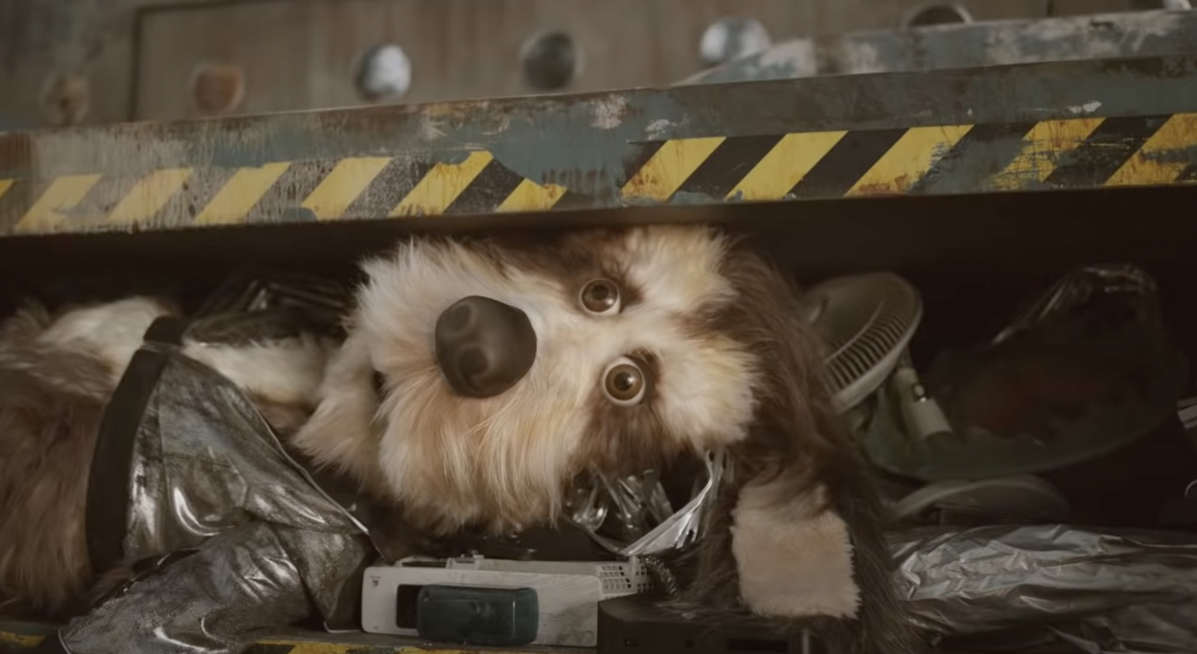 The animatronic dog lays helplessly in a trash compactor.