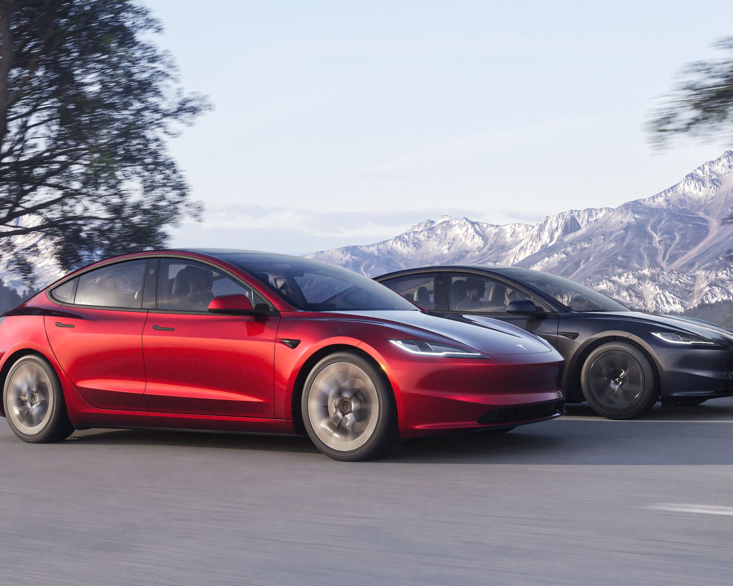 Two Tesla Model 3s shown driving on a mountain road, one red and one gray.