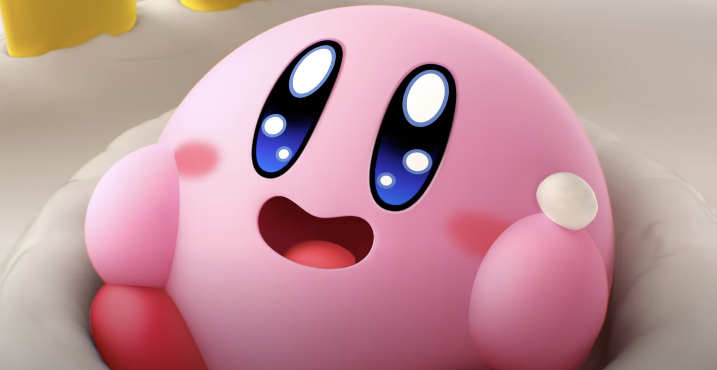 Screenshot from Kirby’s Dream Buffet in which a pink circular blob like creature with huge eyes no nose, rosy cheeks, and a wide open mouth, sits happily in a pile of cake frosting.