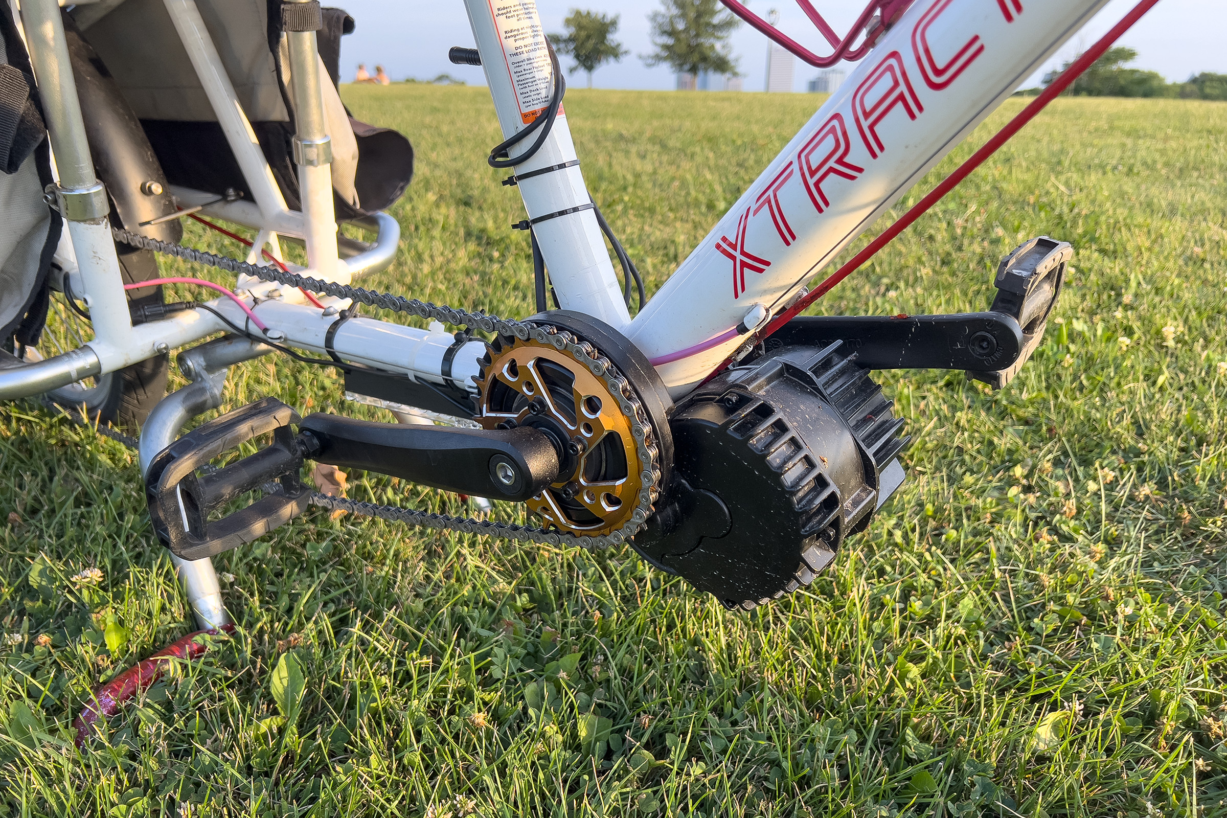 A close-up of the bike’s bottom bracket section after it was finished. It has the e-bike motor, new chainring, and new chain installed. It is sitting in a grassy field at sunset.