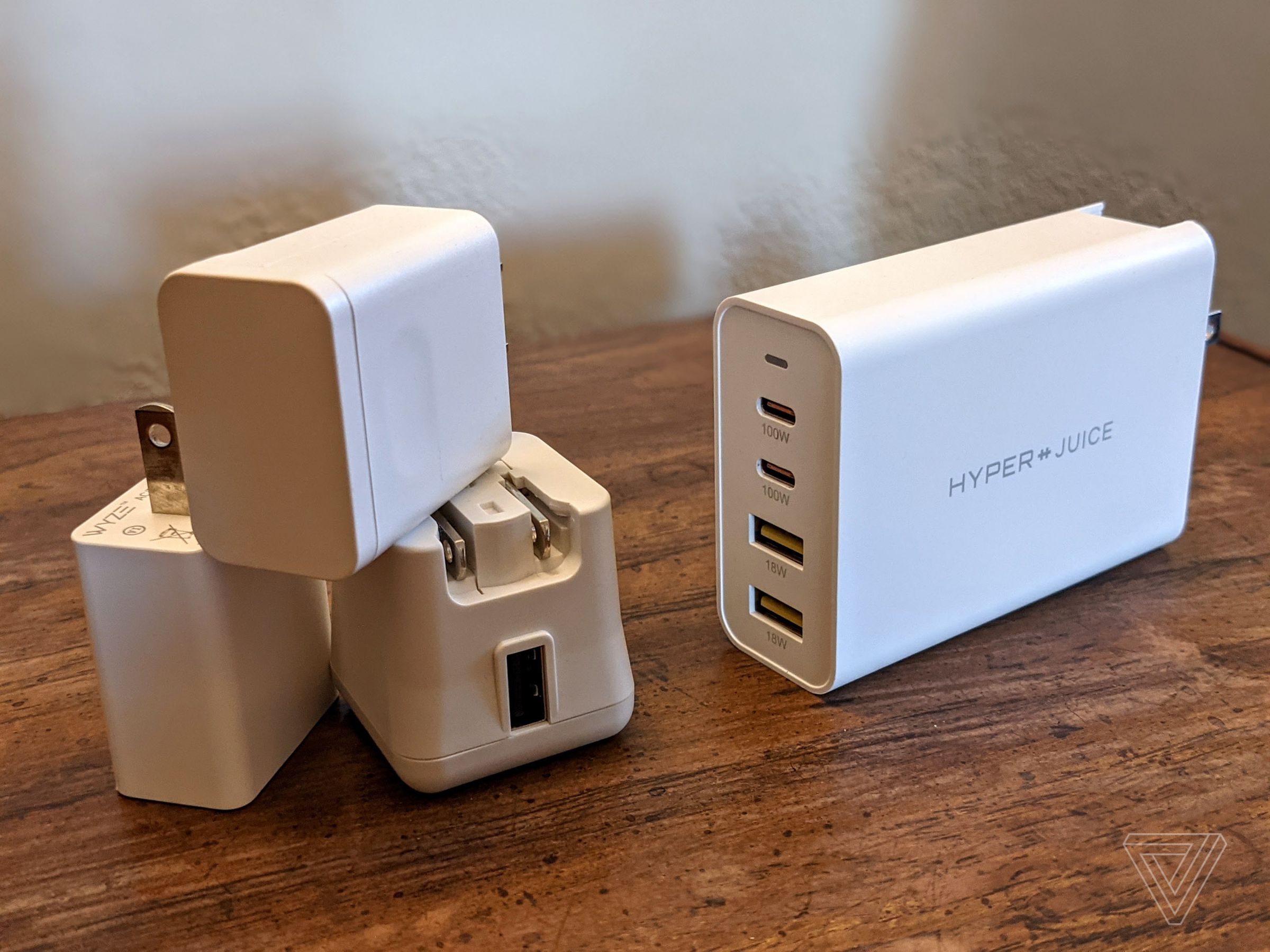 Three old USB-A chargers next to a HyperJuice 100W combo charger with two USB-C and two USB-A ports.