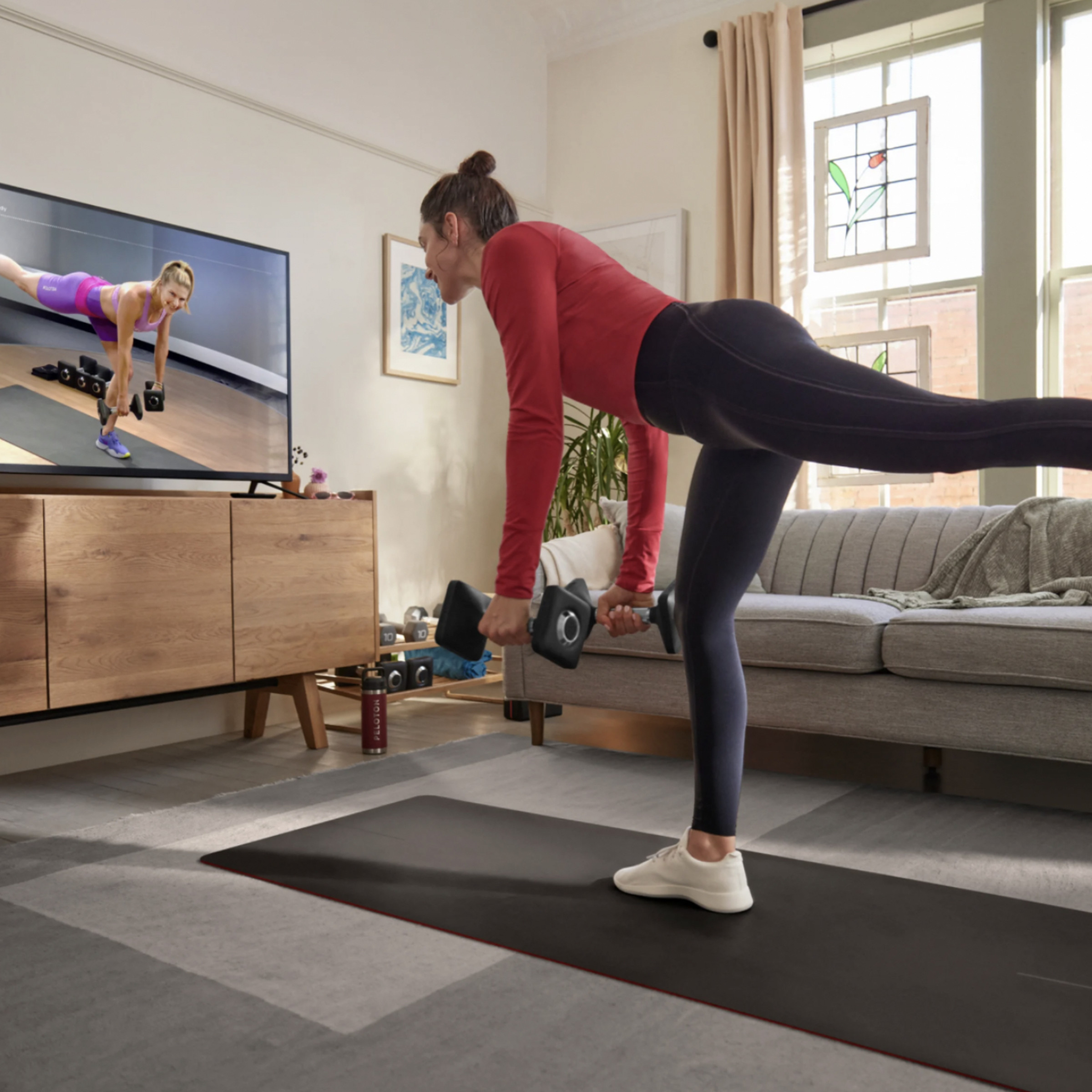 Person stretching in front of TV streaming Peloton subscription content.