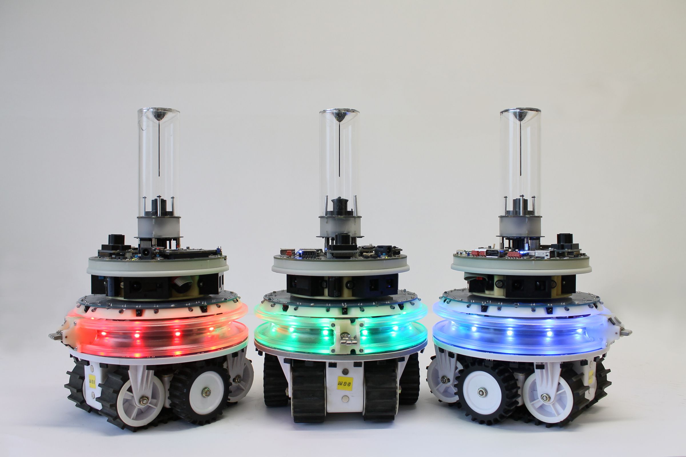 Three autonomous robots with LEDs in different colors.