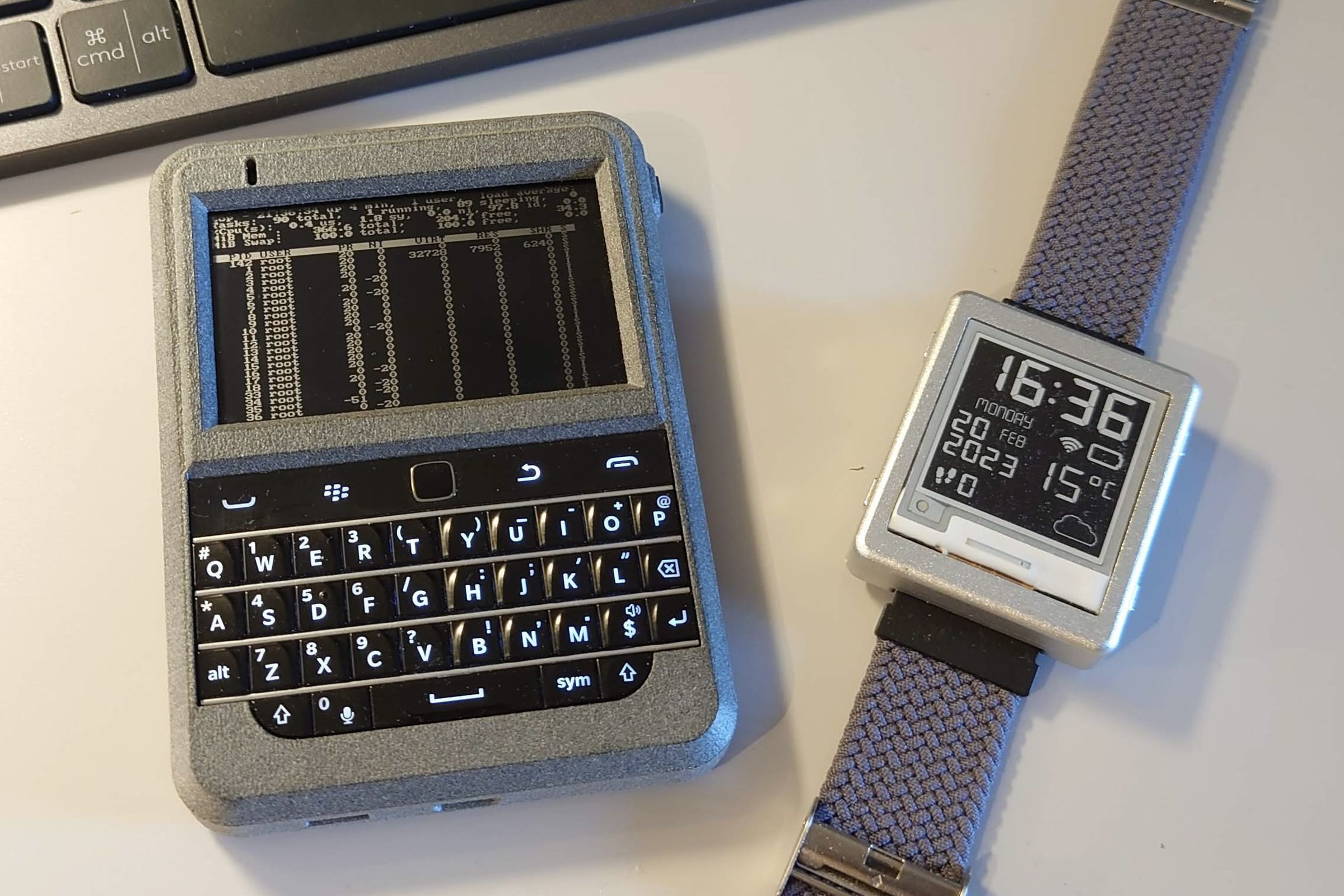 A Beepberry installed inside a 3D-printed shell next to a Pebble-like ‘Watchy’ smartwatch.