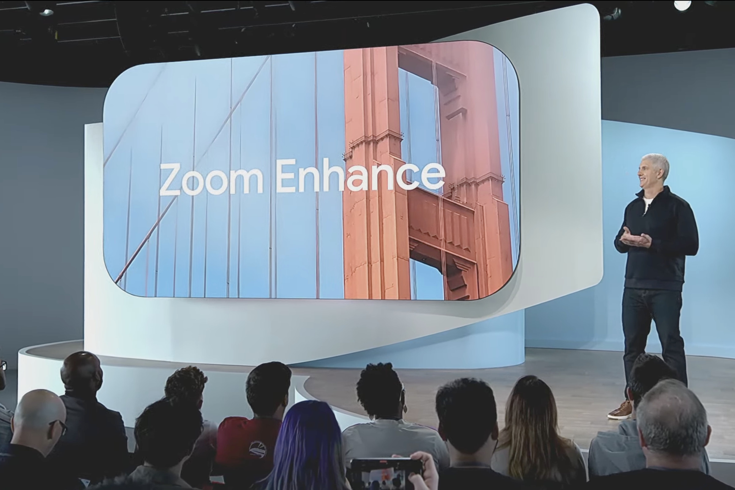 Rick Osterloh standing next to a screen showing “Zoom Enhance.”