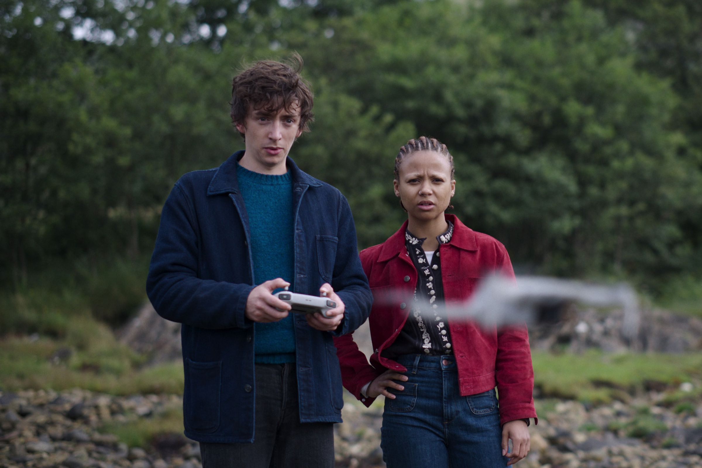 Davis (Samuel Blenkin) and Pia (Myha’la Herrold) standing on a beach using a drone.