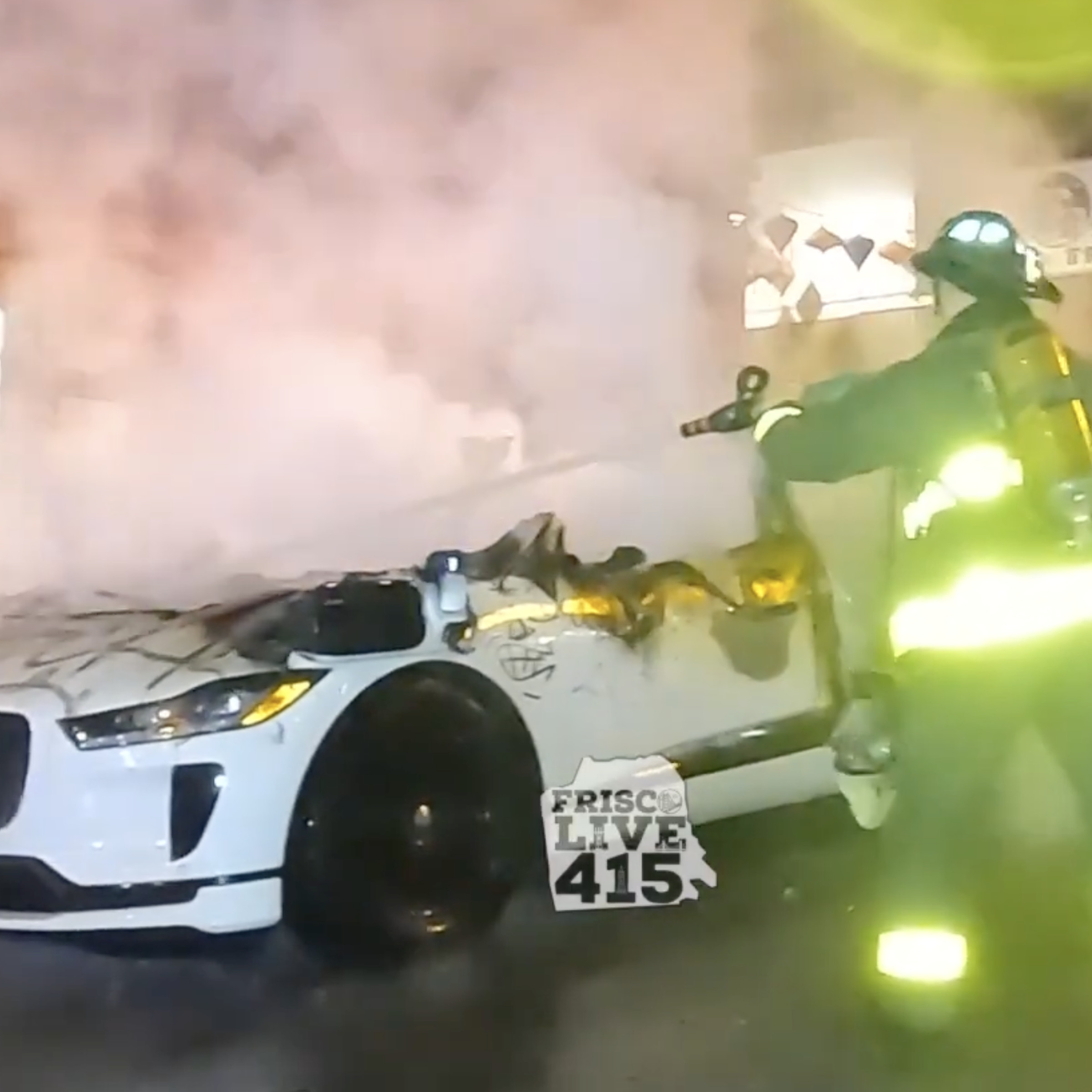 Firefighters spraying a Waymo car.