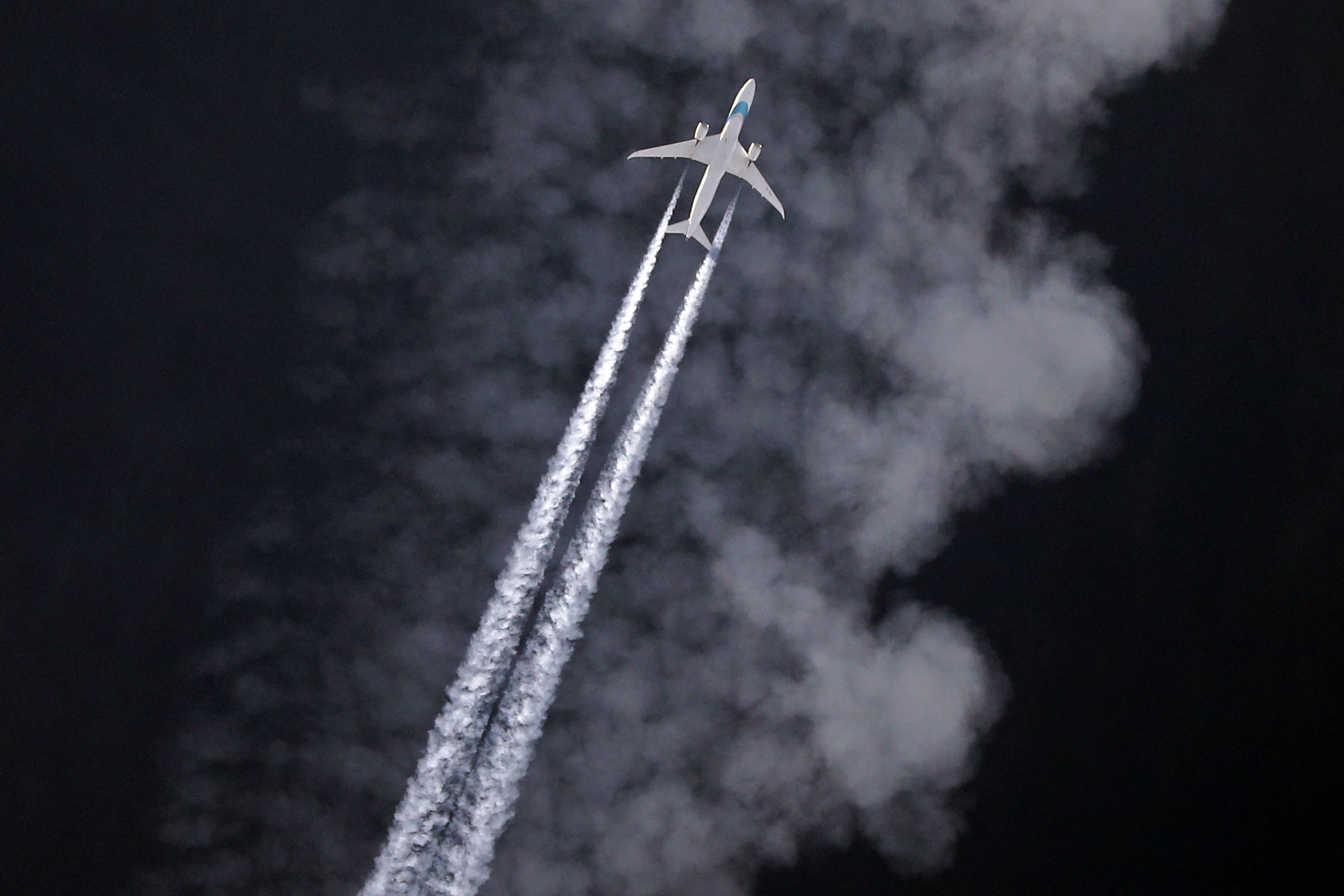 A plane flying with contrails behind it 