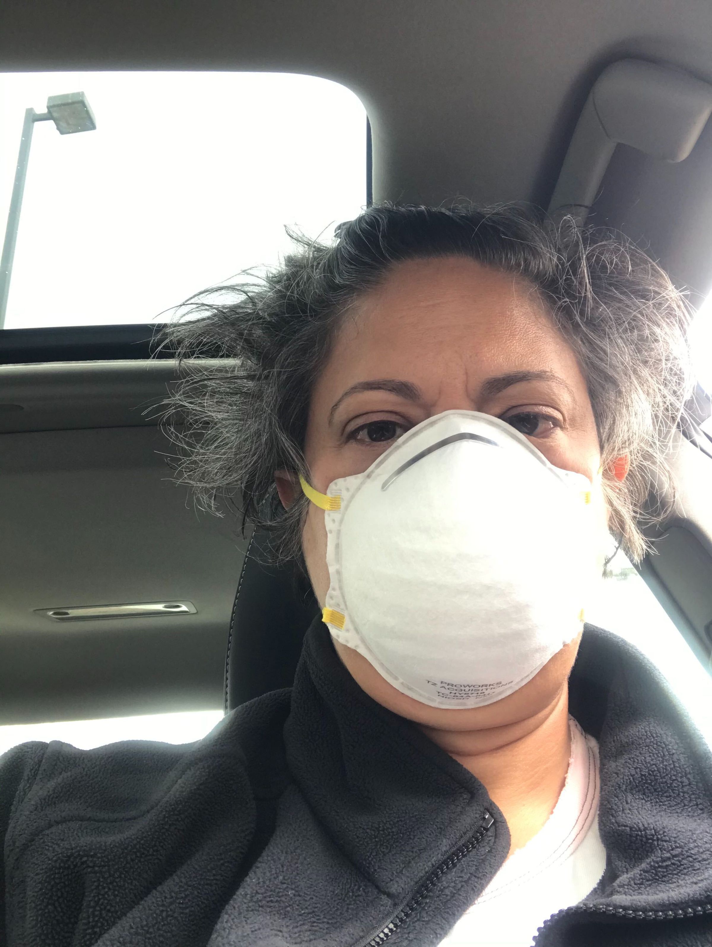 A selfie photo of Rachel in her car wearing a protective face mask.