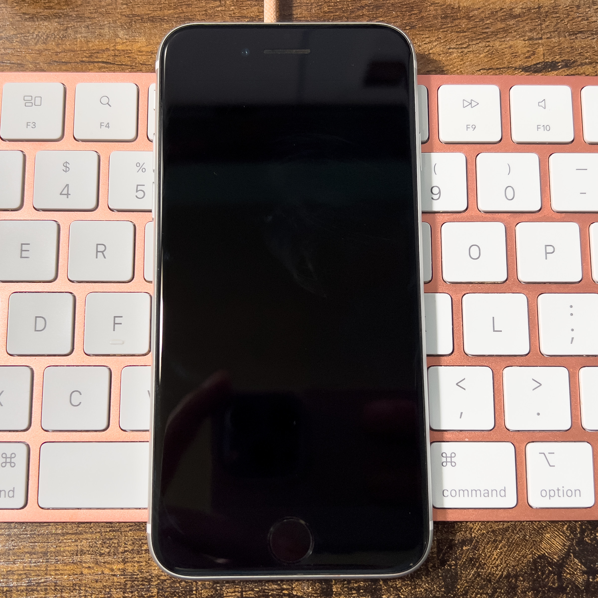 A picture of an iPhone SE laying on a Magic Keyboard.