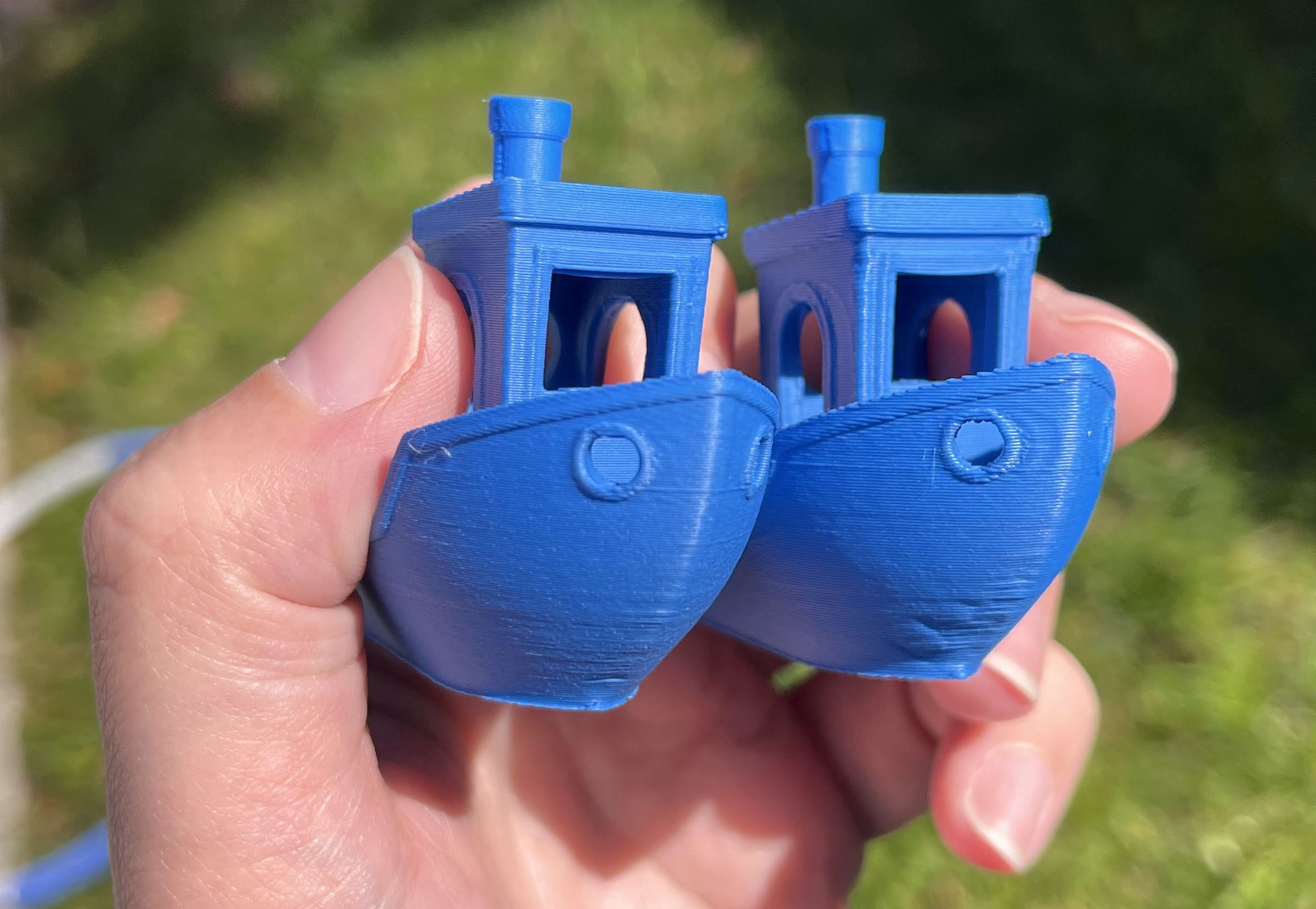 Two blue 3D printed boats with obvious layer lines as you go up and down.