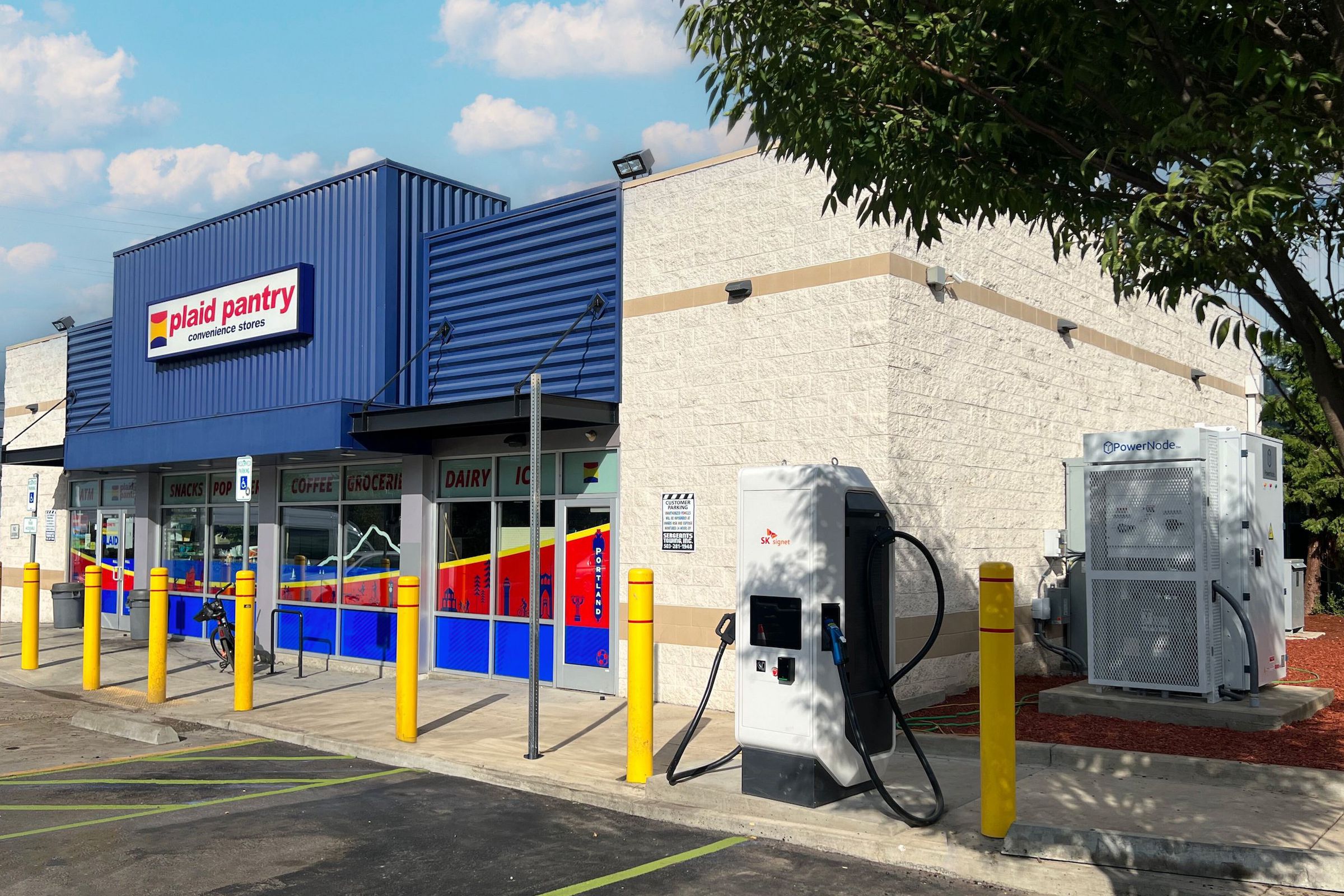 paid pantry convenience store from with parking spots and one ev charger and a transformer box at the side of the building