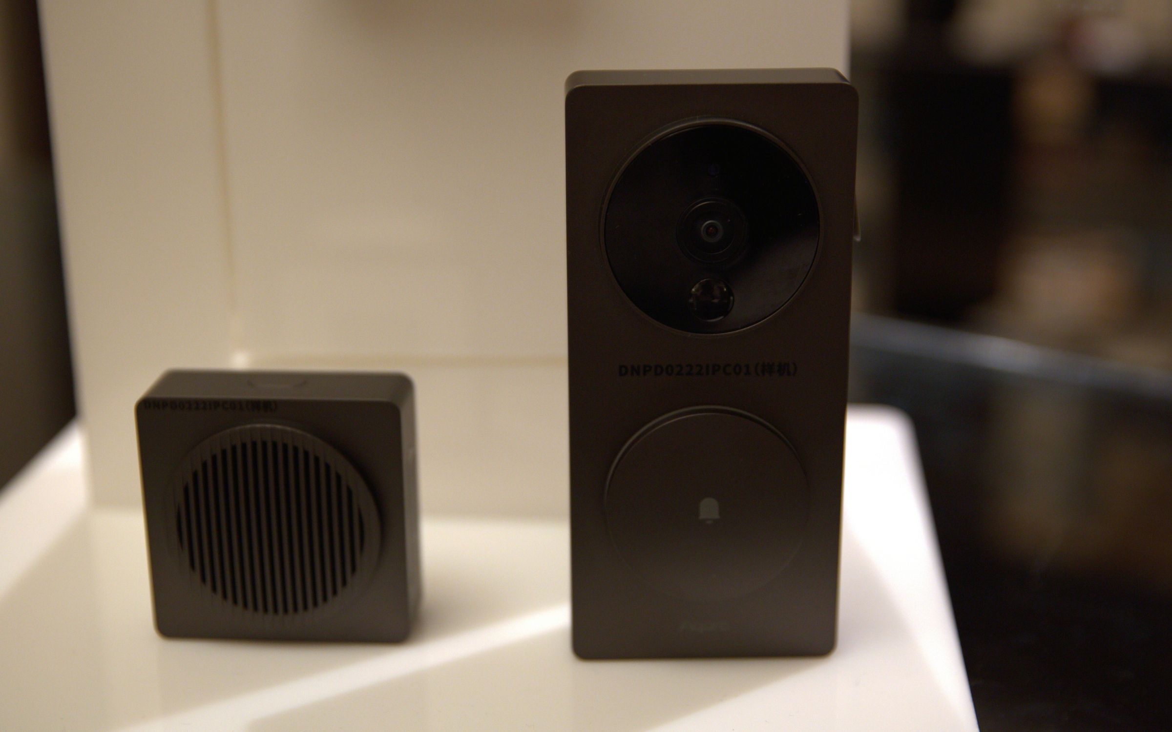 The Aqara Video Doorbell G4, with the chime speaker on the left and the main video doorbell on the right. they are placed on a white table at CES 2023.