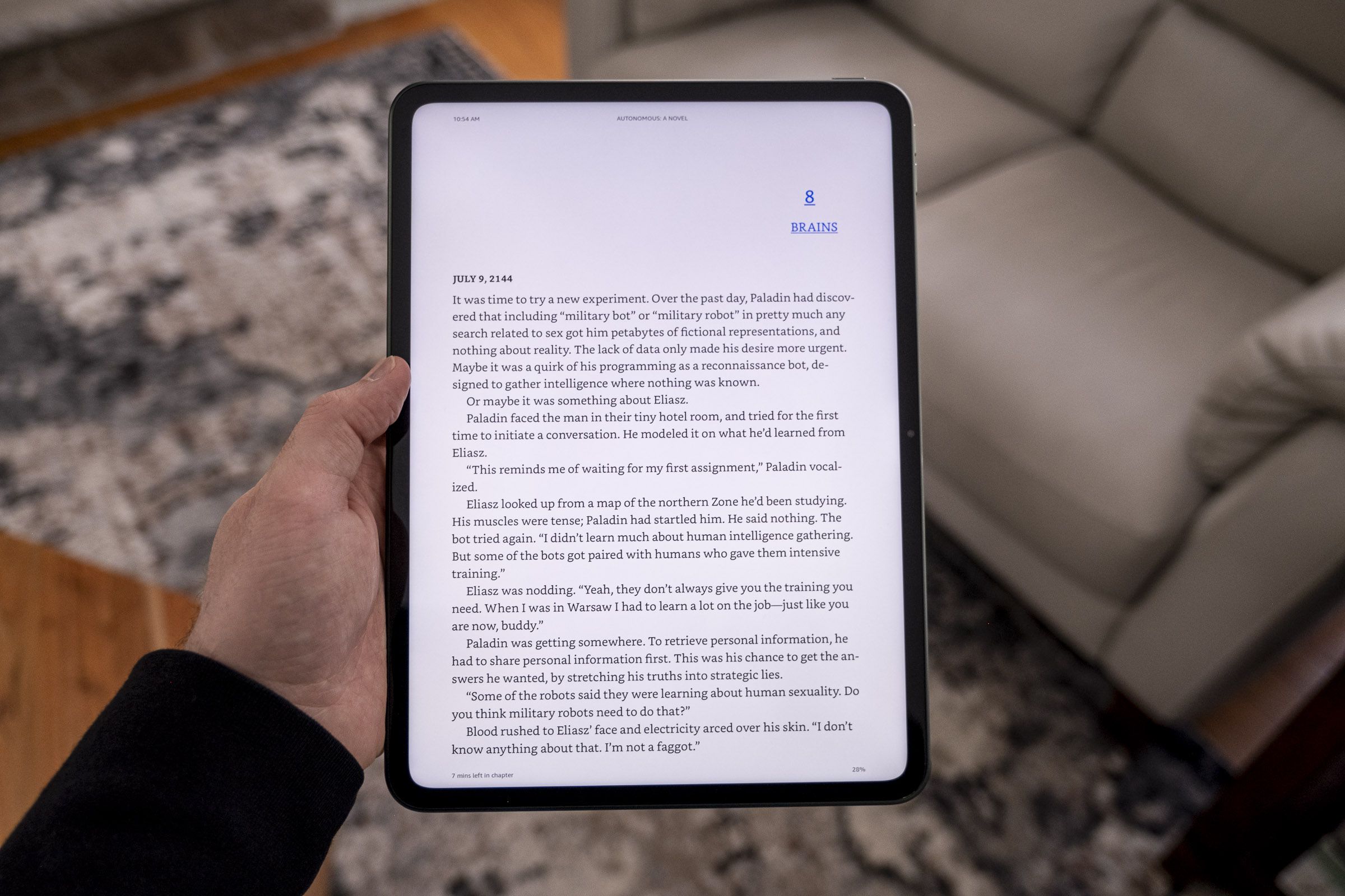 A OnePlus Pad held in portrait orientation displaying a book in the Kindle app