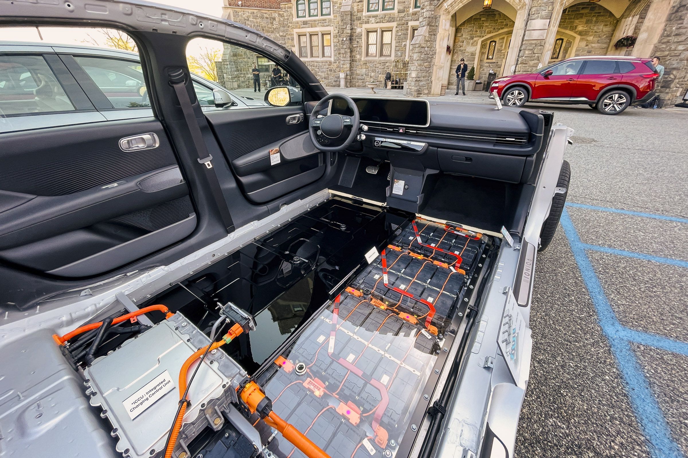 a car with the top and interior stripped, one sidewall remains and the floor is battery cells and cables