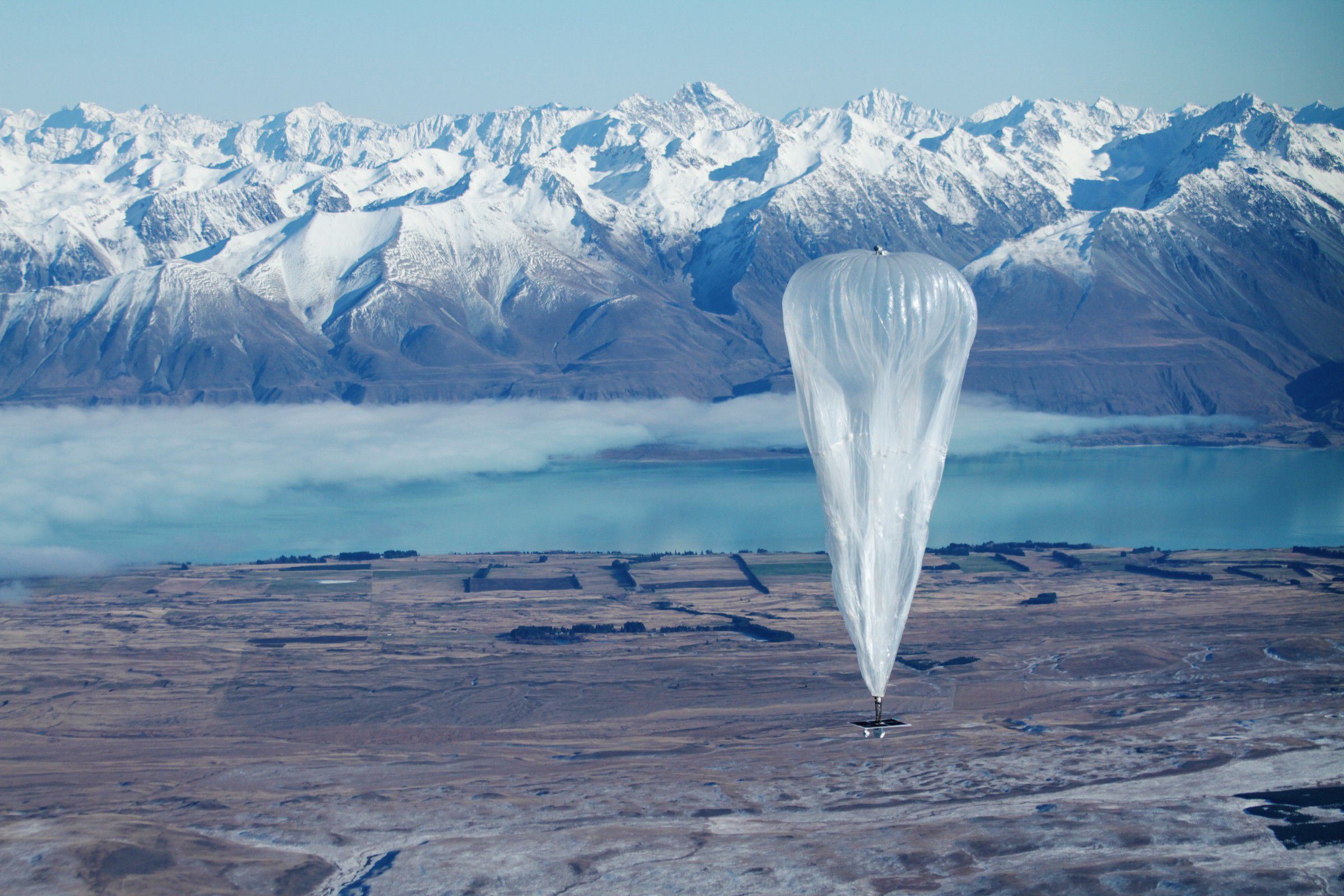 Image of a balloon floating in front of a snow-covered mountain range.