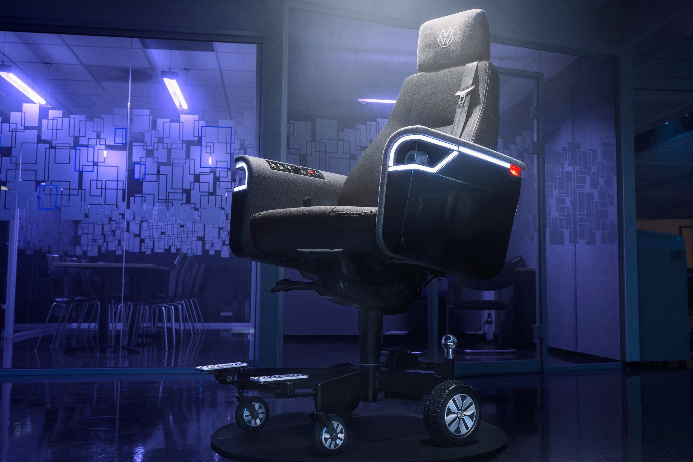 Volkswagen’s chair is ready to party with LED trim around its working headlights, but it’s also ready to drive with a car seatbelt and dedicated metal footrests. The mostly black chair is depicted here in a purple-lit office space with glass doors.