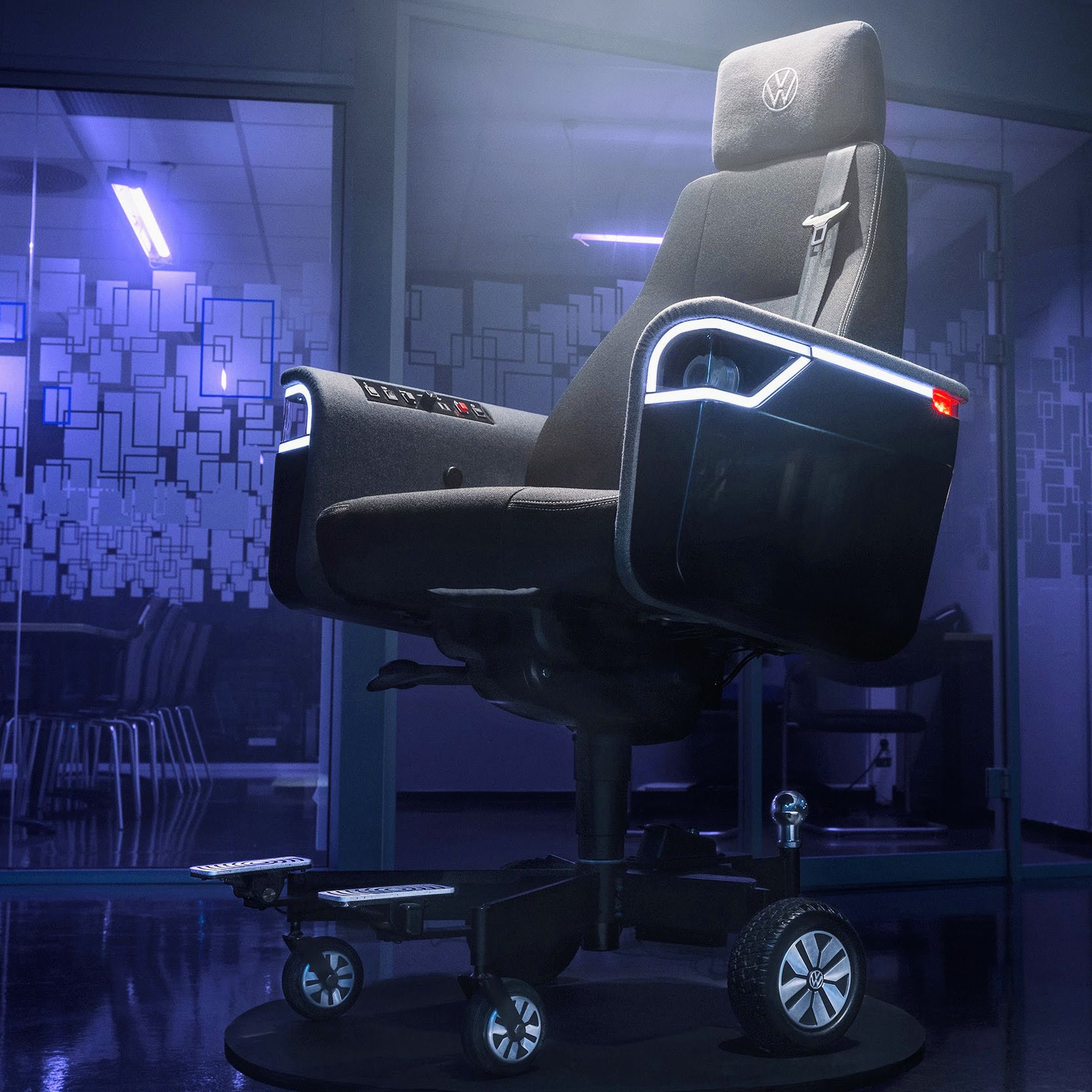 Volkswagen’s chair is ready to party with LED trim around its working headlights, but it’s also ready to drive with a car seatbelt and dedicated metal footrests. The mostly black chair is depicted here in a purple-lit office space with glass doors.