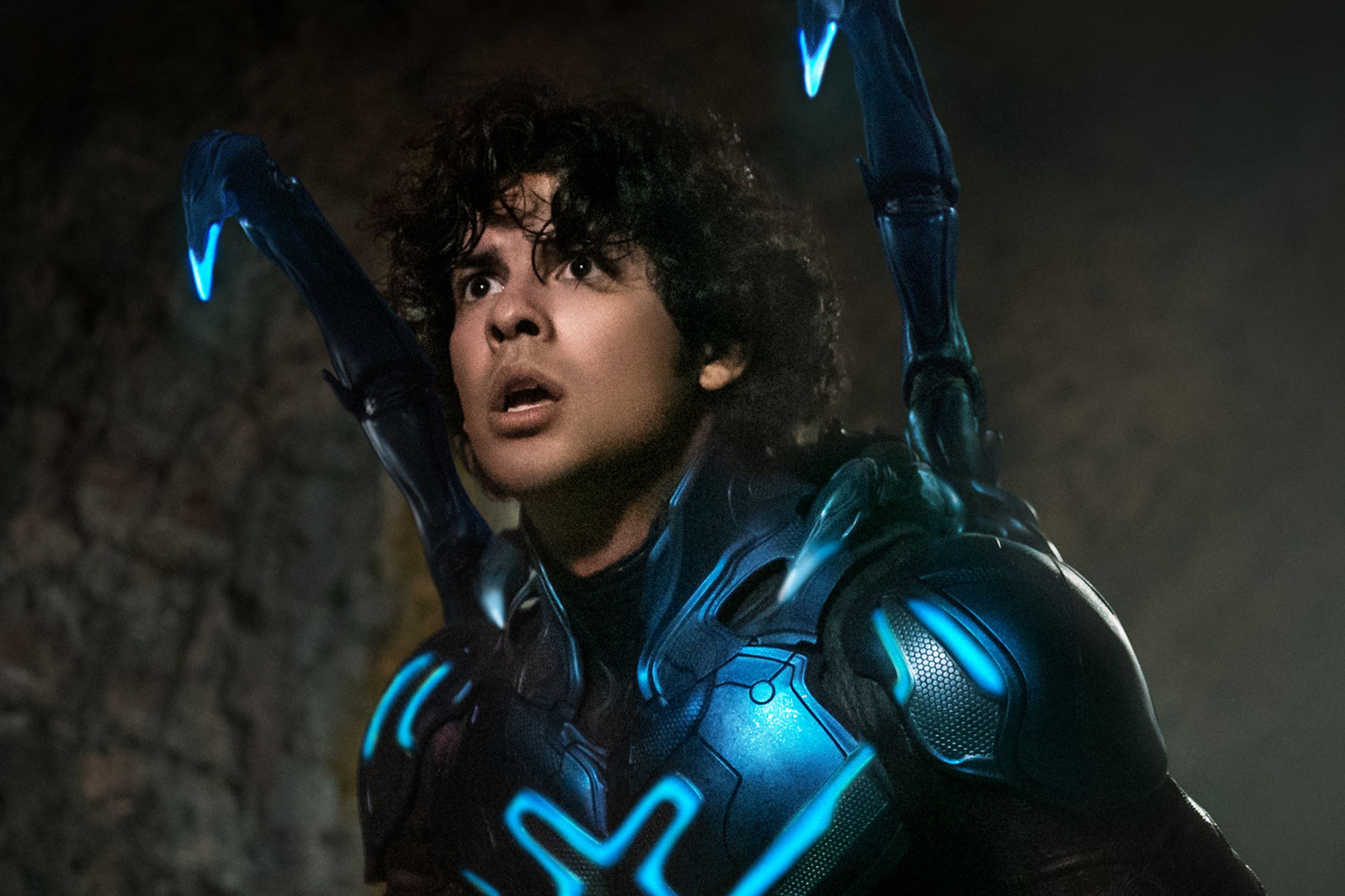A young man in a dark blue form-fitting exoskeleton adorned with glowing neon pining across the chest.