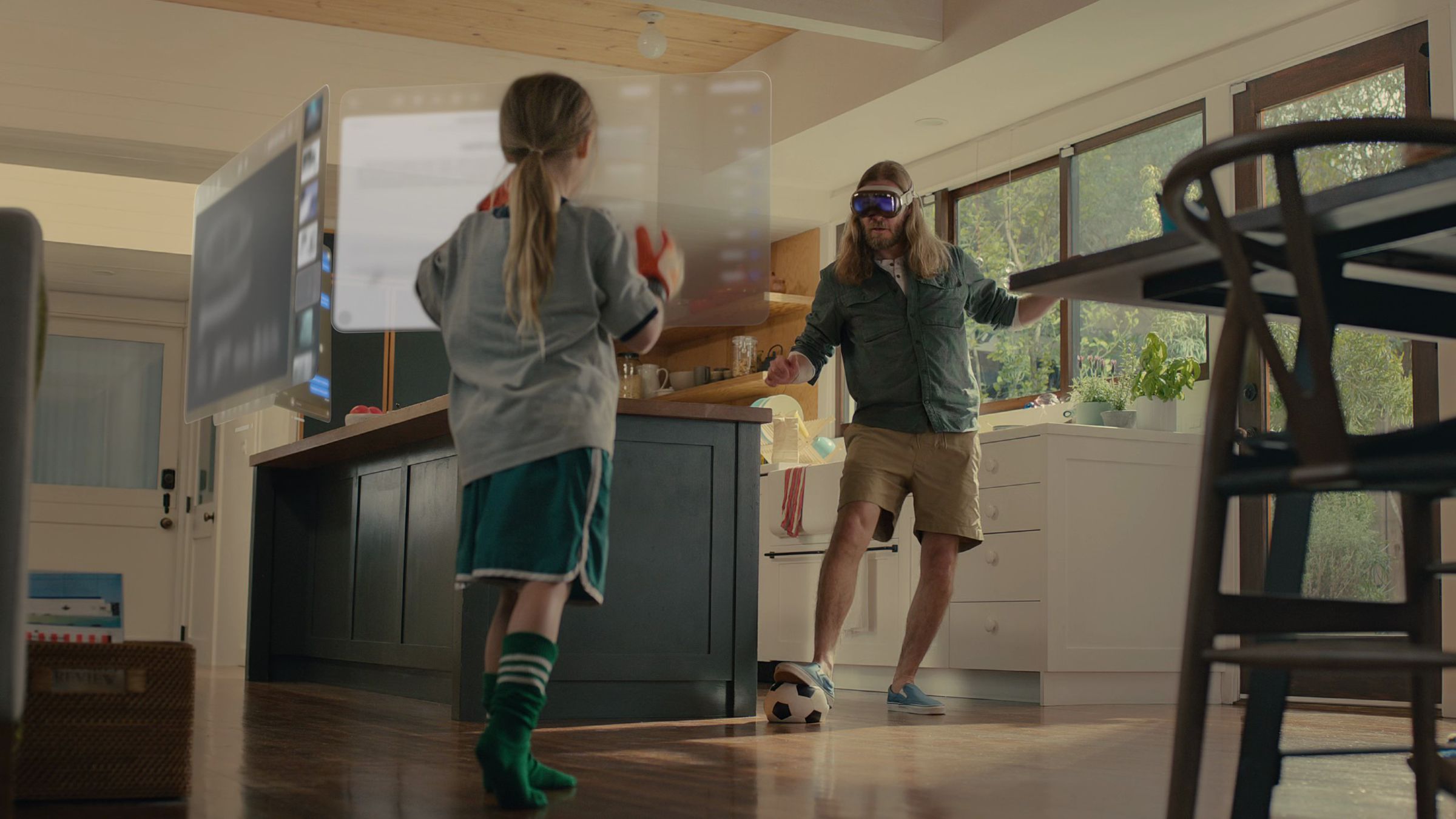 Still capture from keynote video showing parent with headset kicking a soccer ball to child.