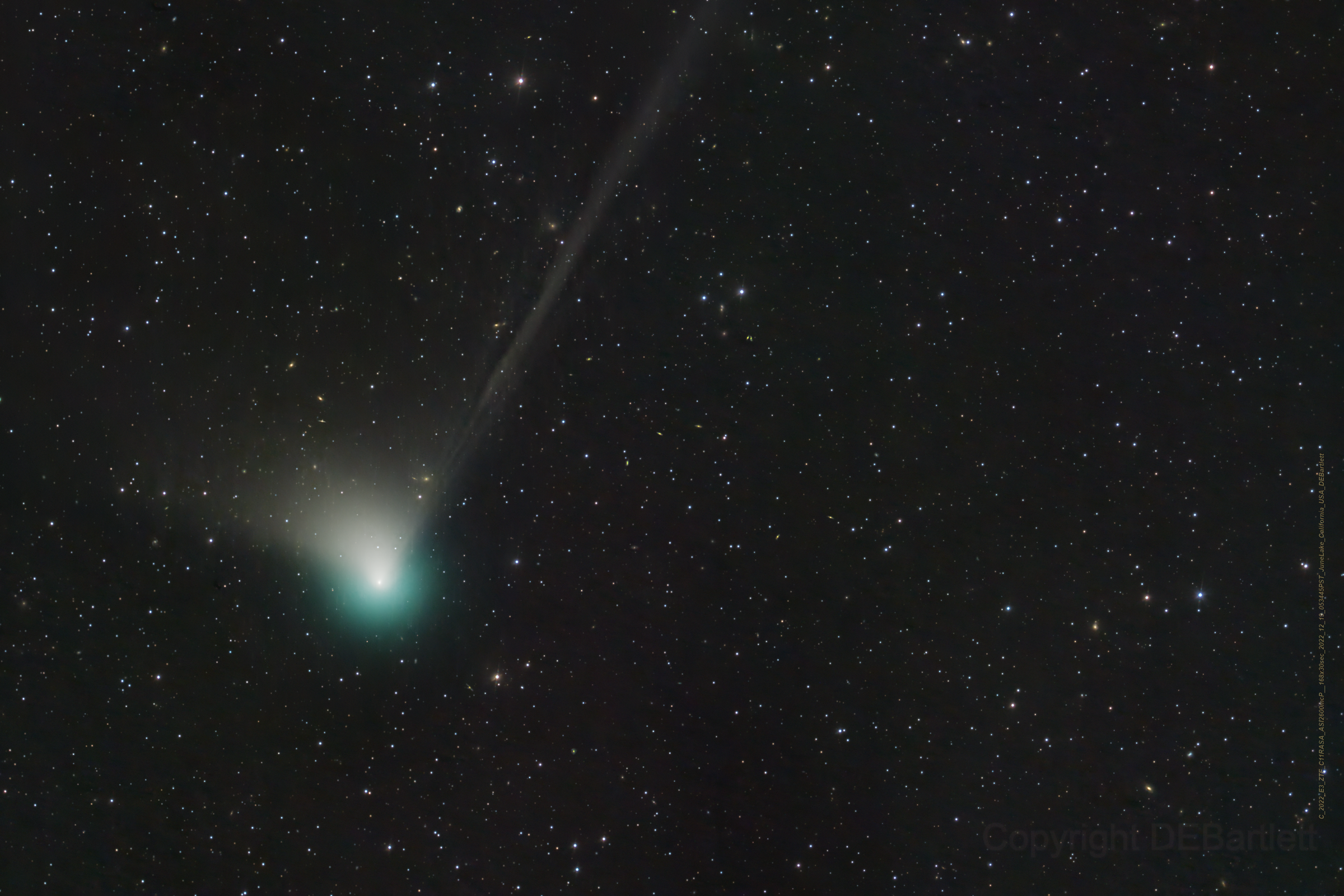 A comet glows white and green.