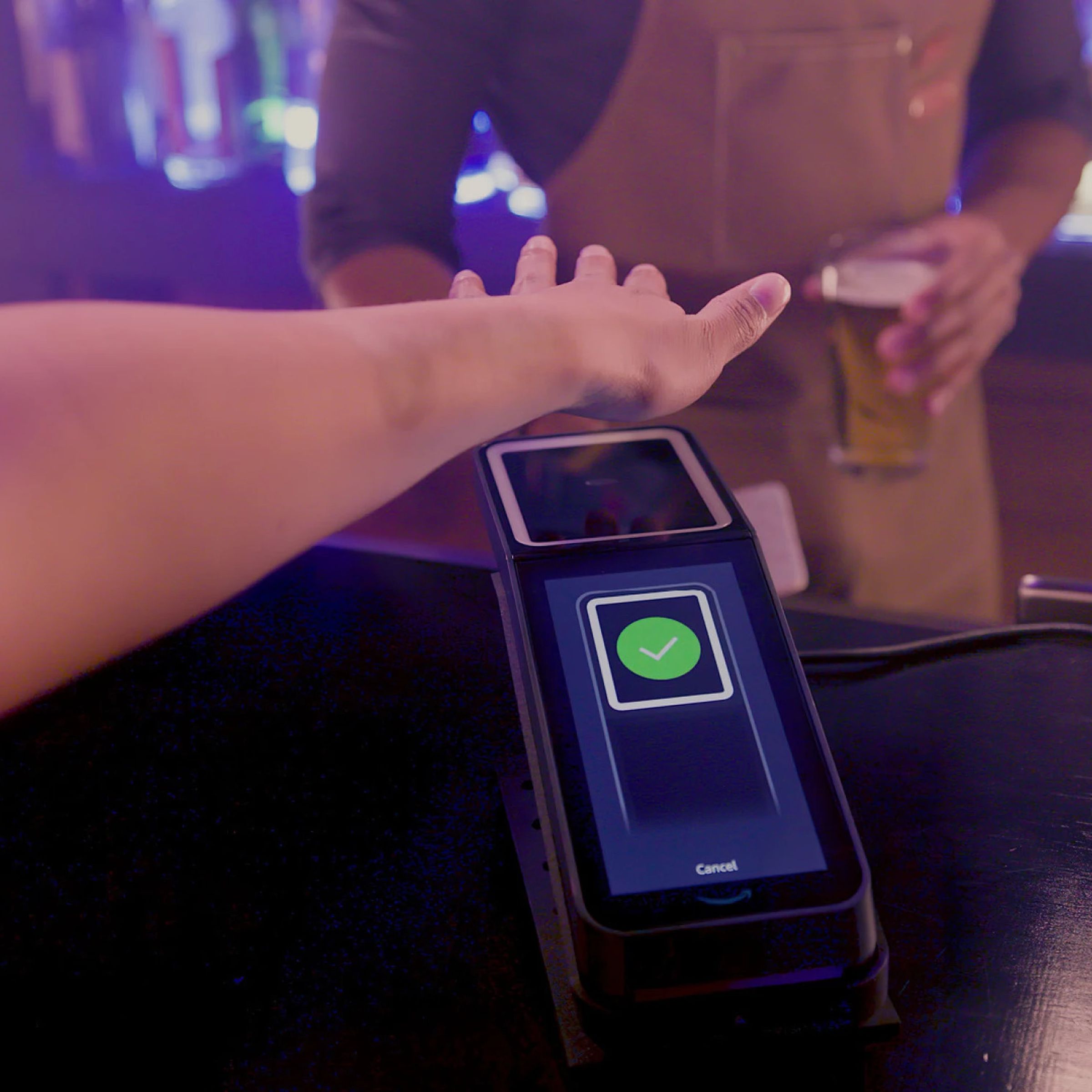 An image showing someone hovering their palm over a scanner at a bar