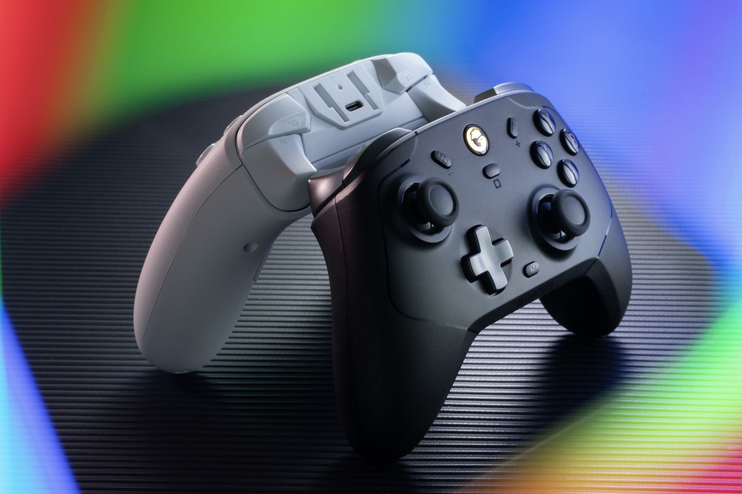 Black and white controllers standing back to back with rainbow colors surrounding them.
