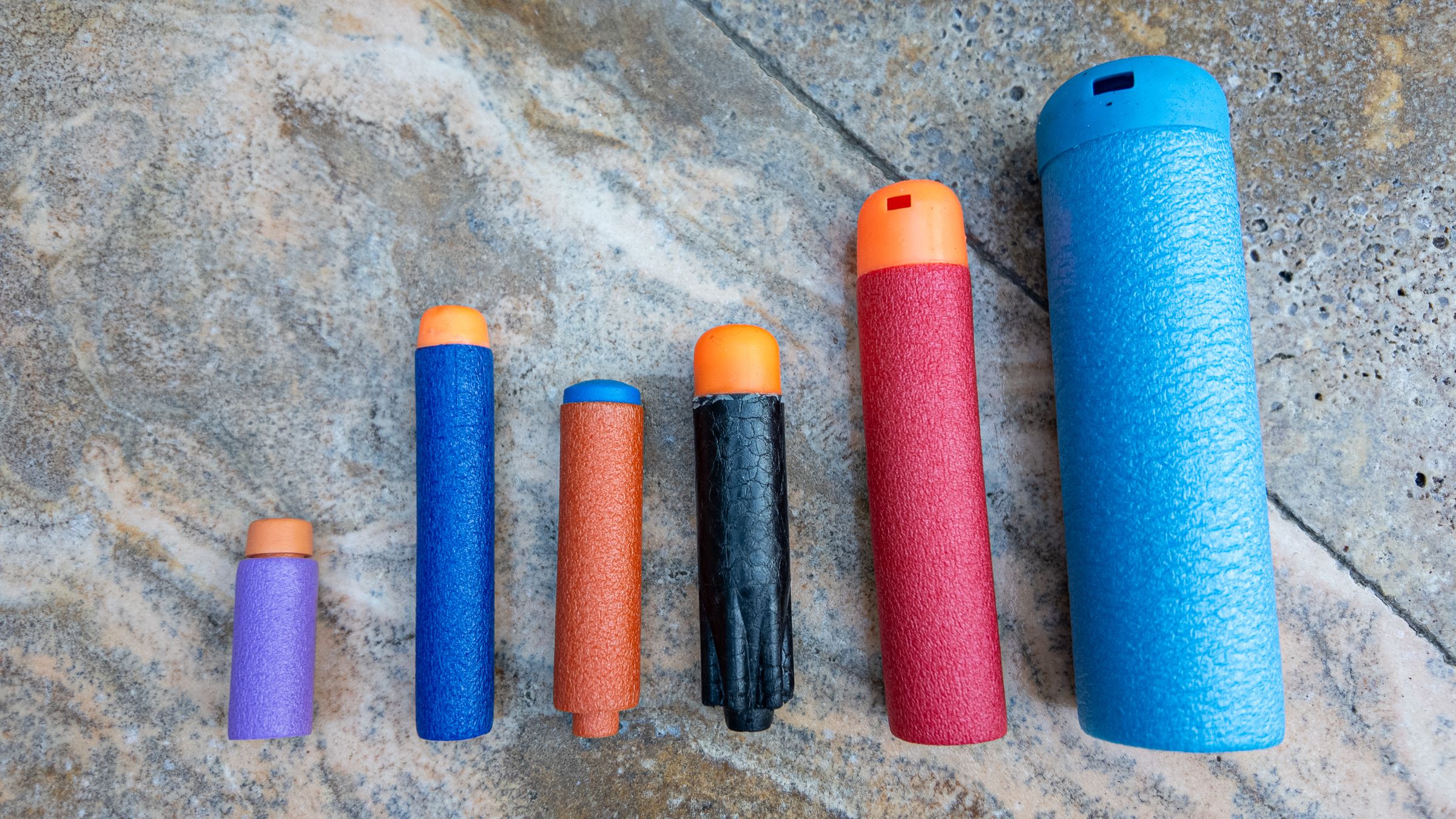 Nerf’s N1 dart (orange), compared to the Elite (deep blue), Ultra (black), Mega and Mega XL (red, light blue), and a Worker short dart (purple) favored by the nerf community.