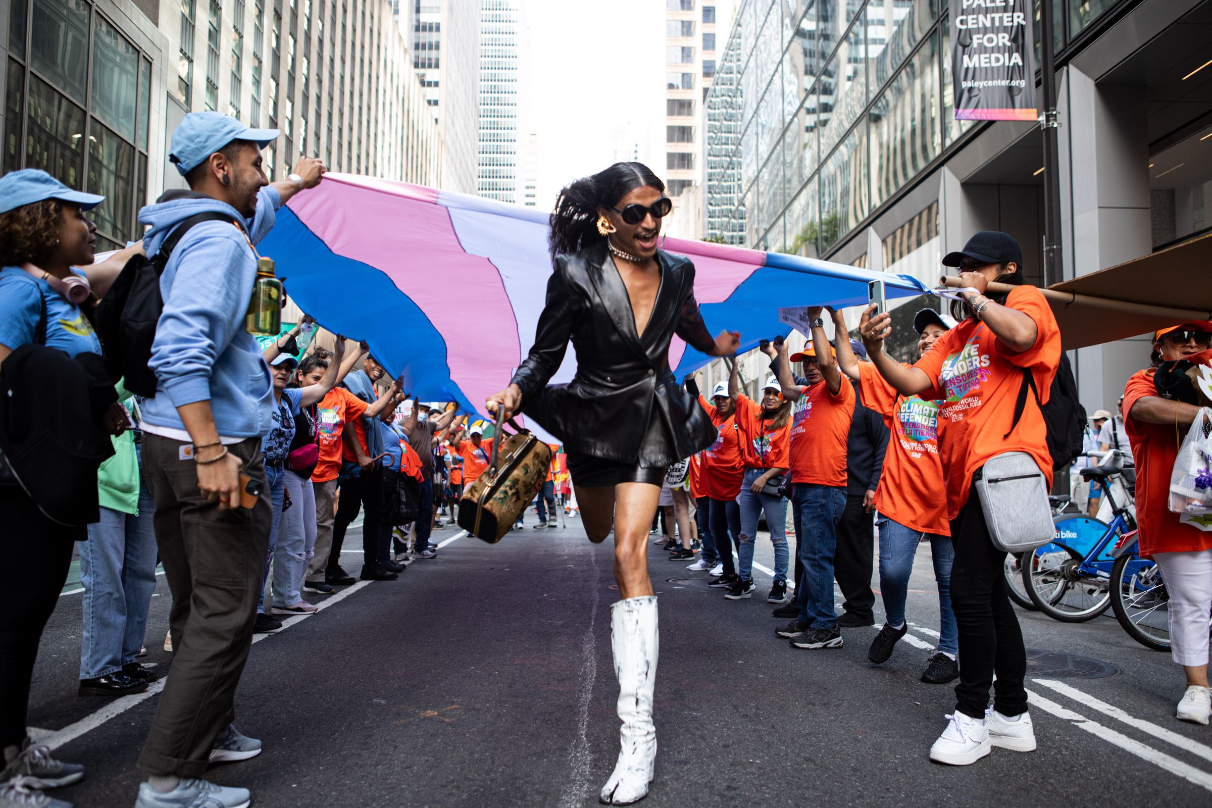 Tiaamé runs under a banner of the transgender flag held by representatives and supporters of the nonprofit Make the Road New York.