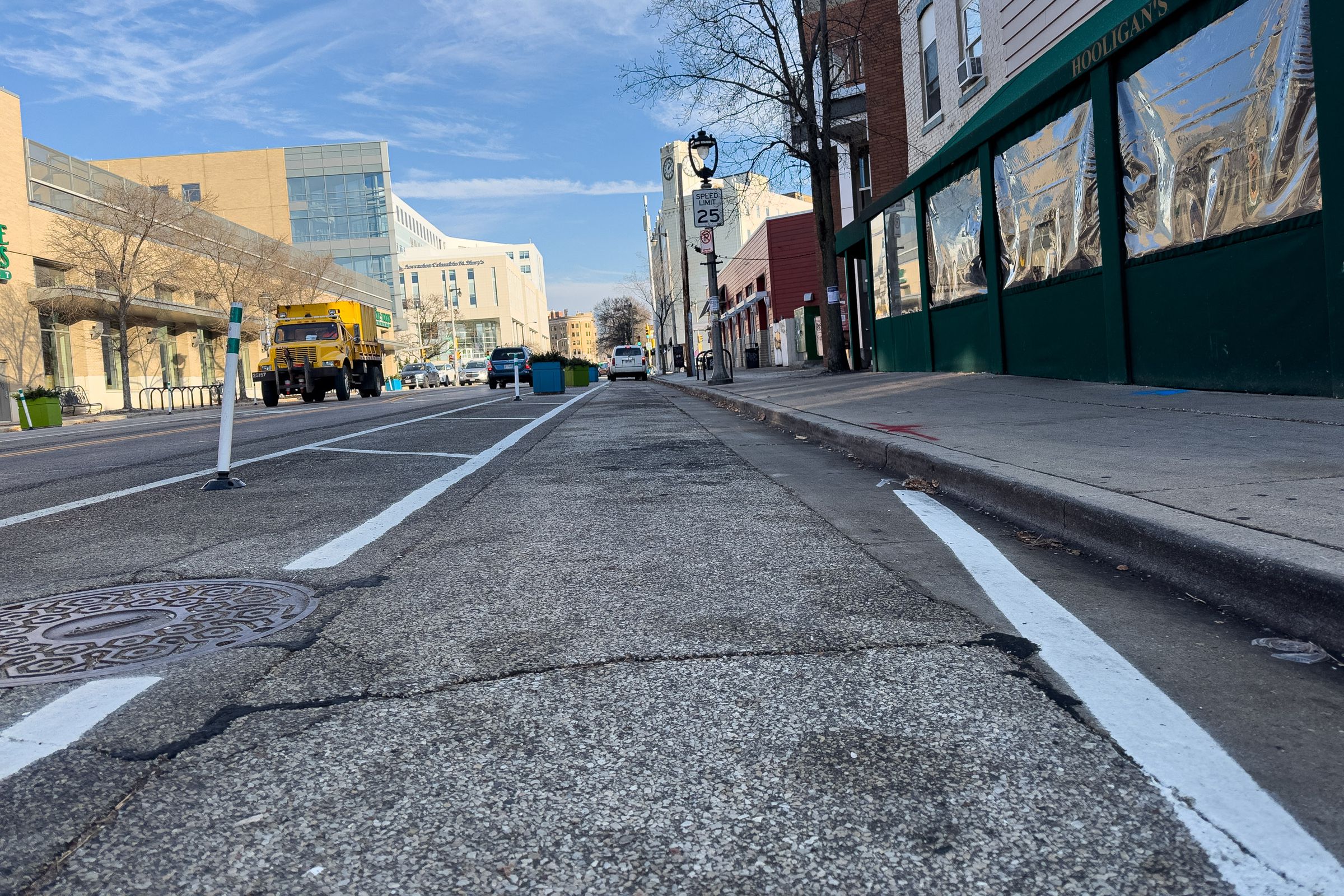A picture of a buffered bike lane in a commercial district. The picture is taken close to the road surface.